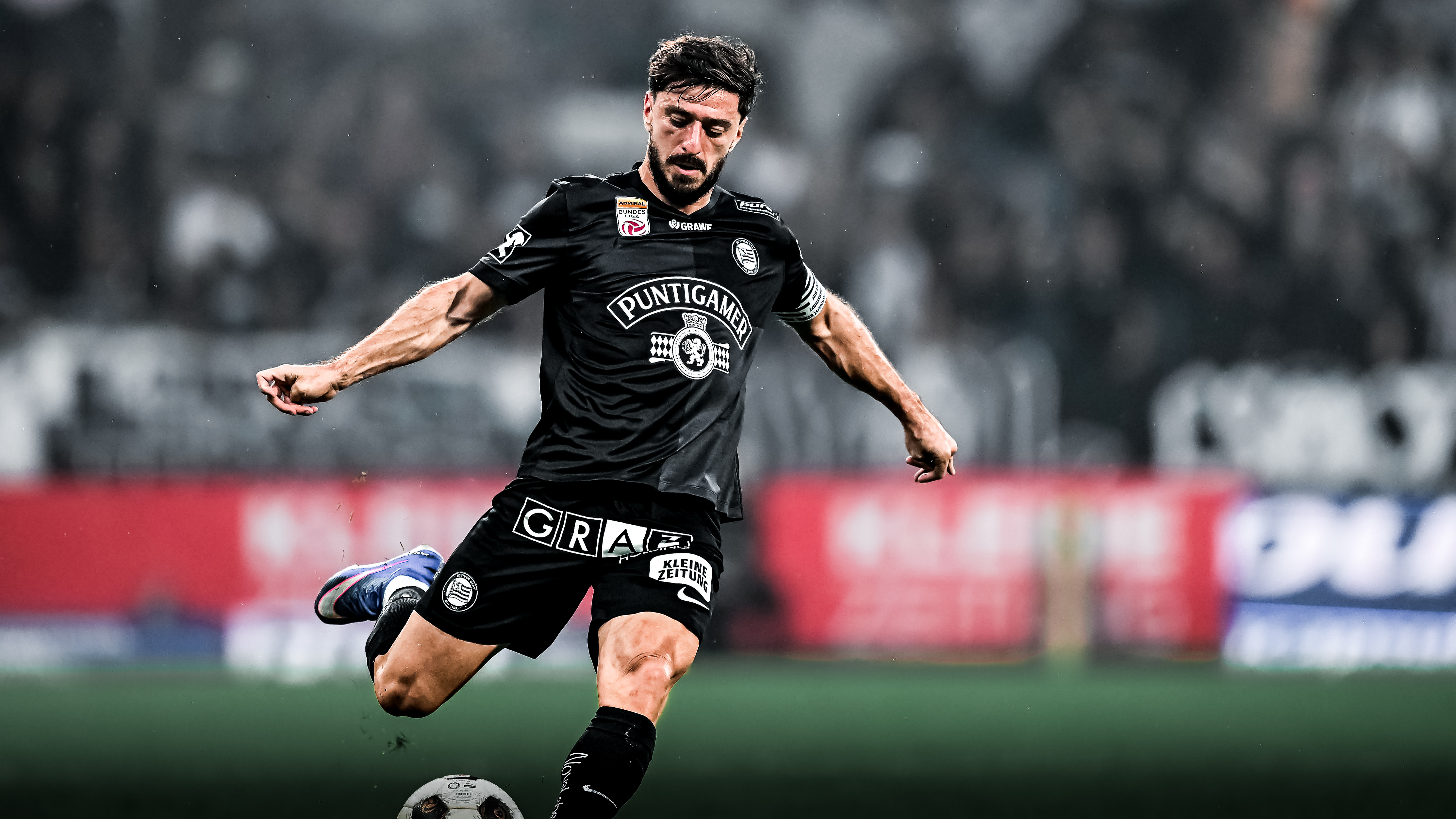 Ein Spieler in einem schwarzen Shirt schießt einen weißen Ball.