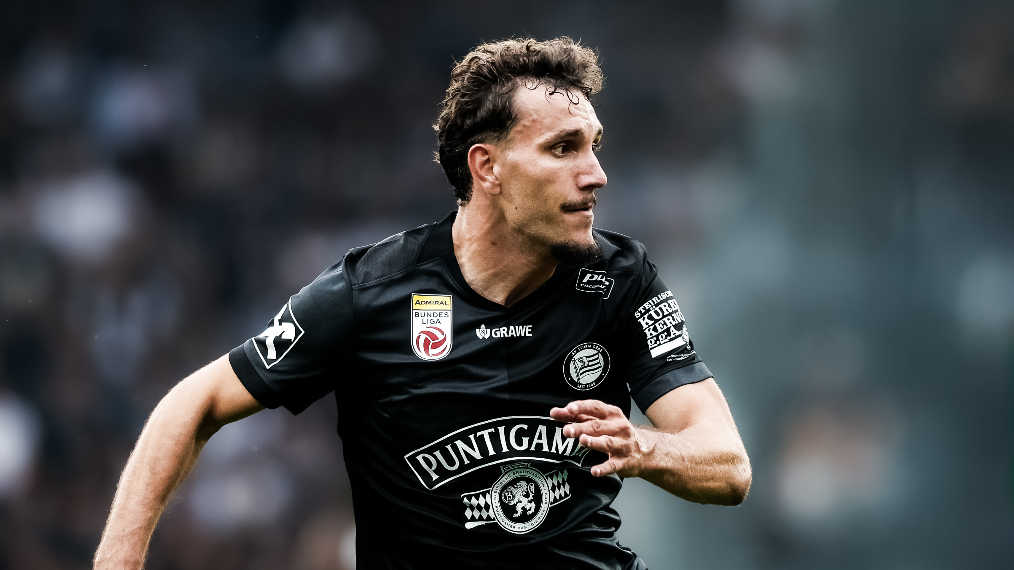 Ein Spieler in einem schwarzen Trikot läuft und schaut nach rechts.