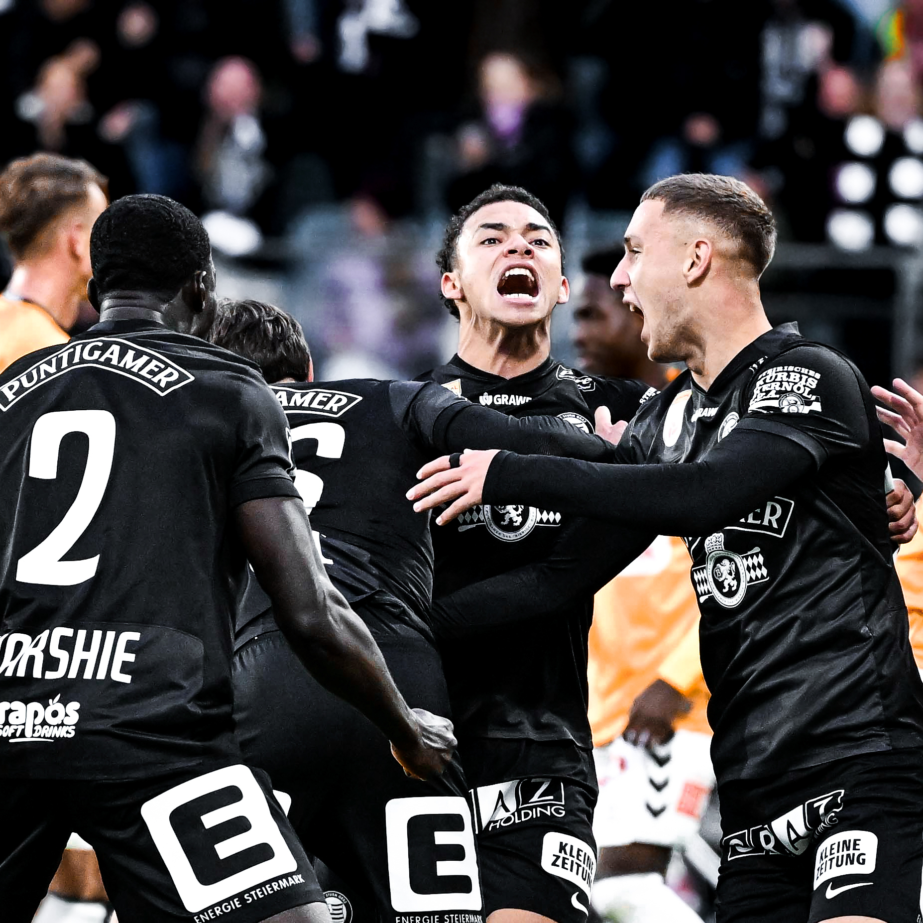 Fünf Spieler in schwarzen Trikots jubeln.