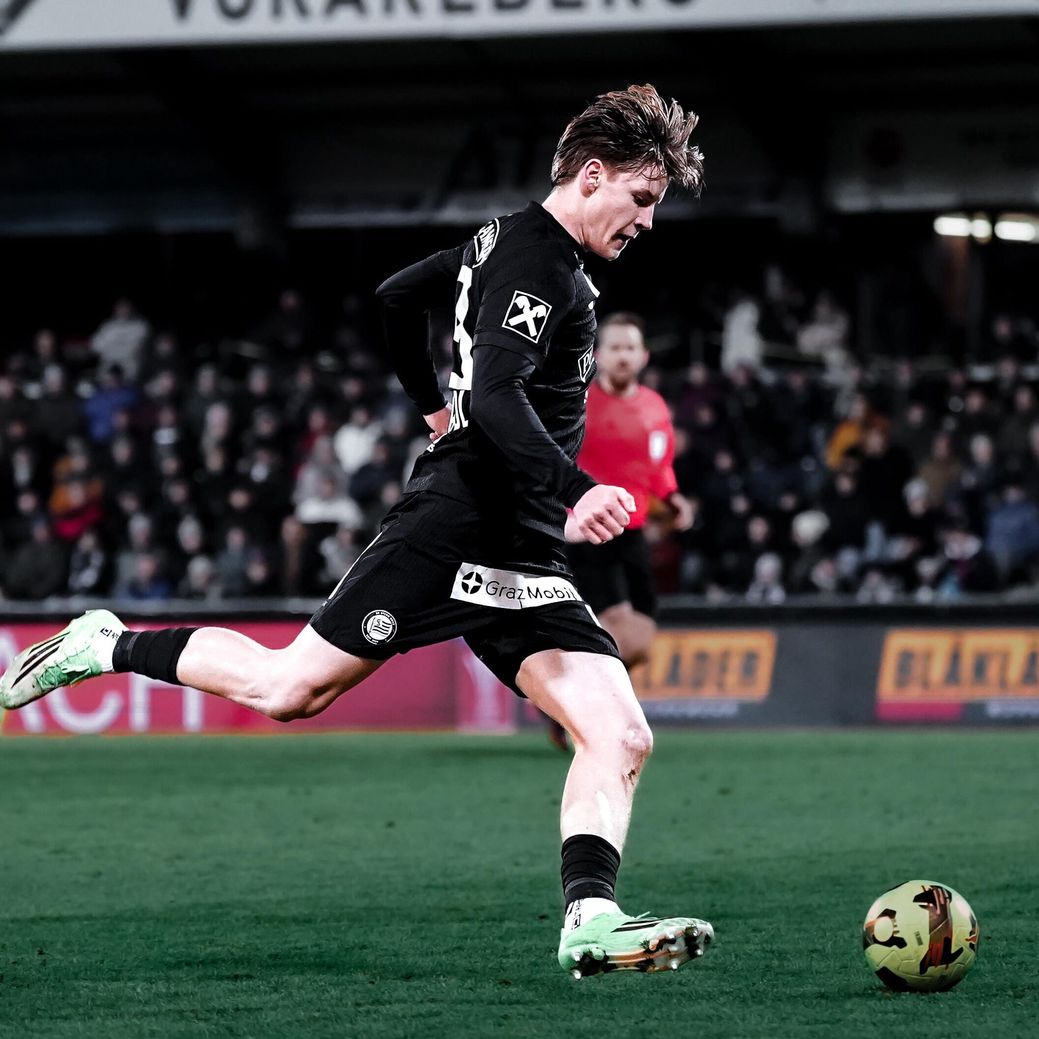 Ein Spieler in einem schwarzen Trikot tritt gegen einen Ball