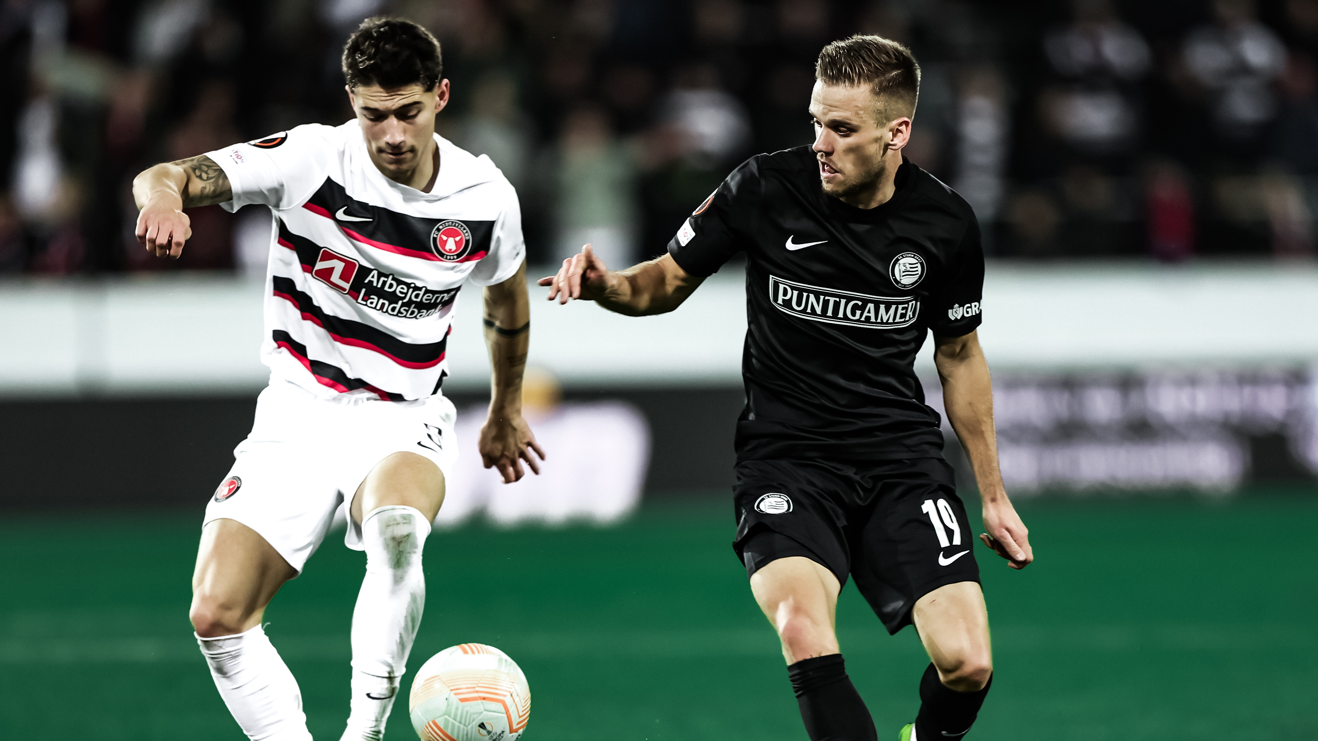 Zweikampf um den Ball von einem Spieler in schwarz und einem in weiß