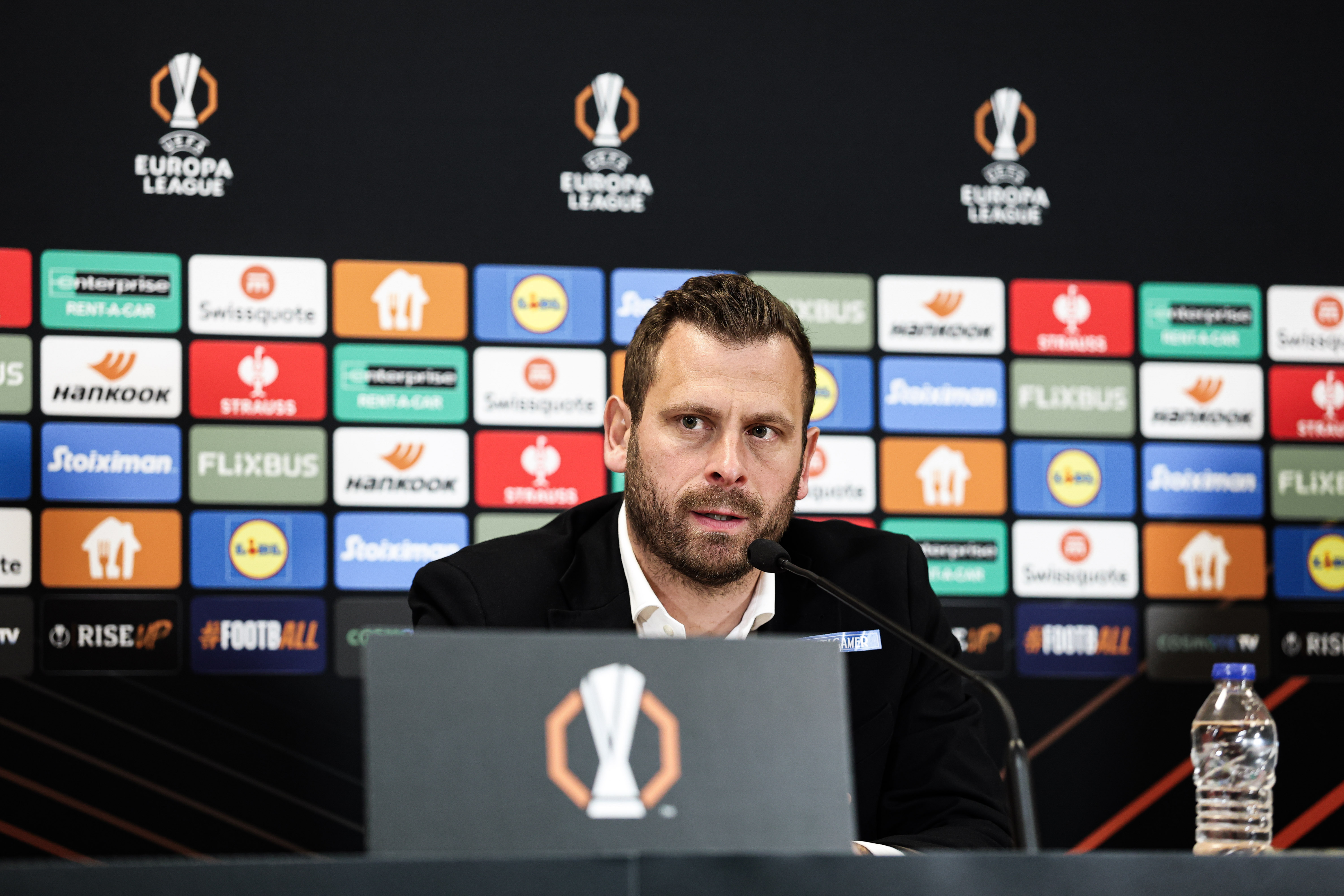 Ein Mann vor vielen Logos auf einer Wand