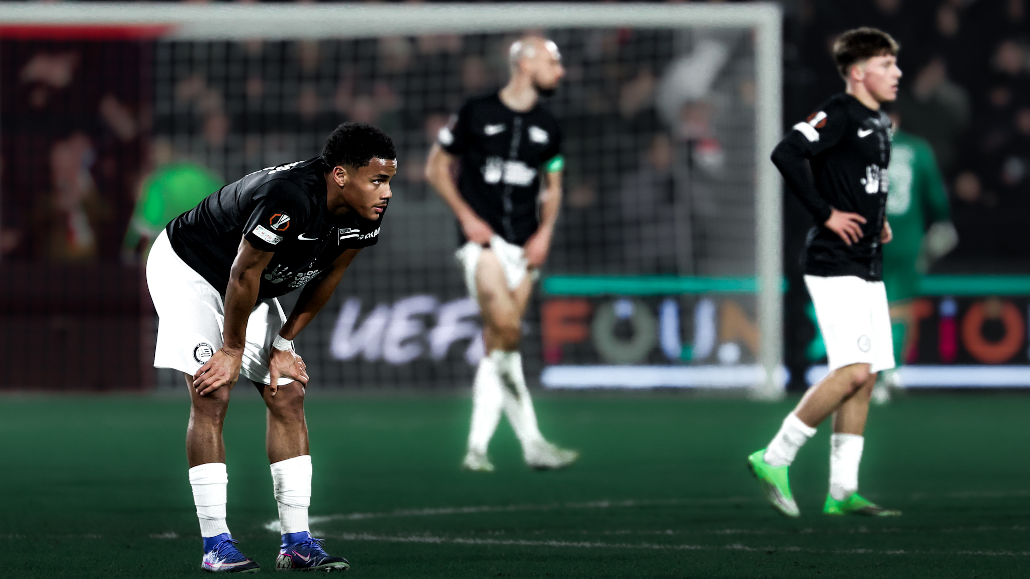 Drei Spieler mit hängenden Köpfen und schwarz-weißen Trikots und Hosen