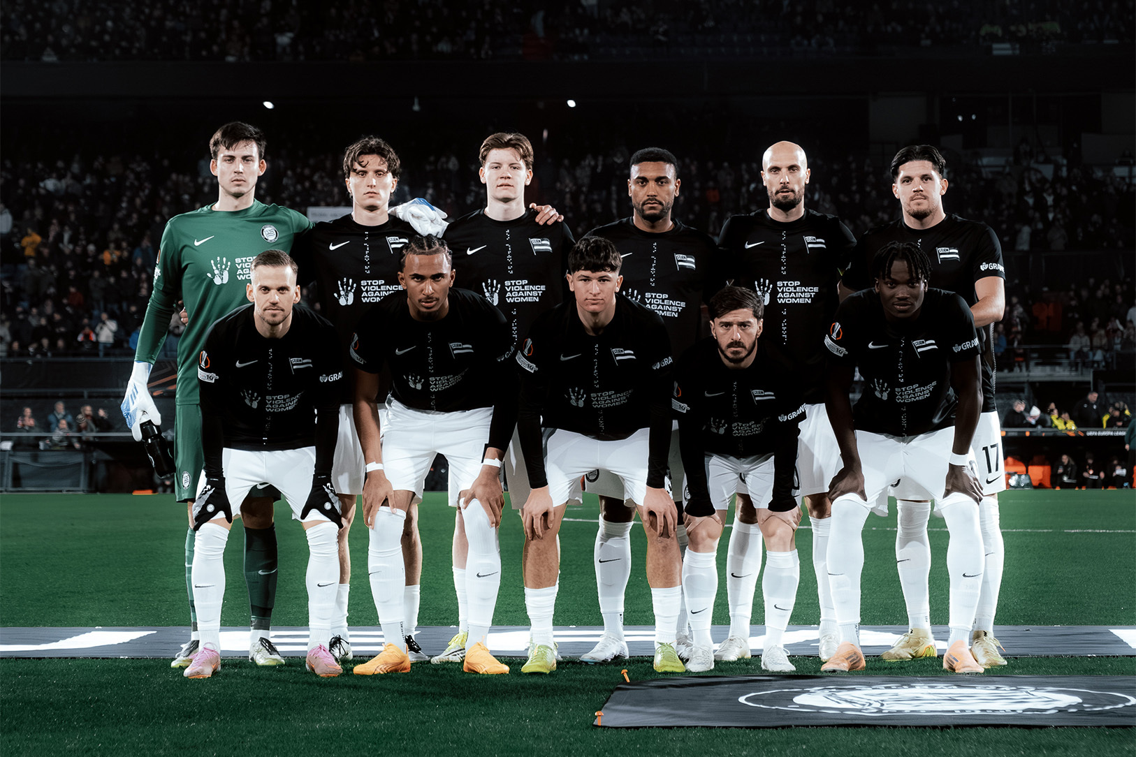 Eine Fußballmannschaft Arm in Arm für ein Foto posierend.