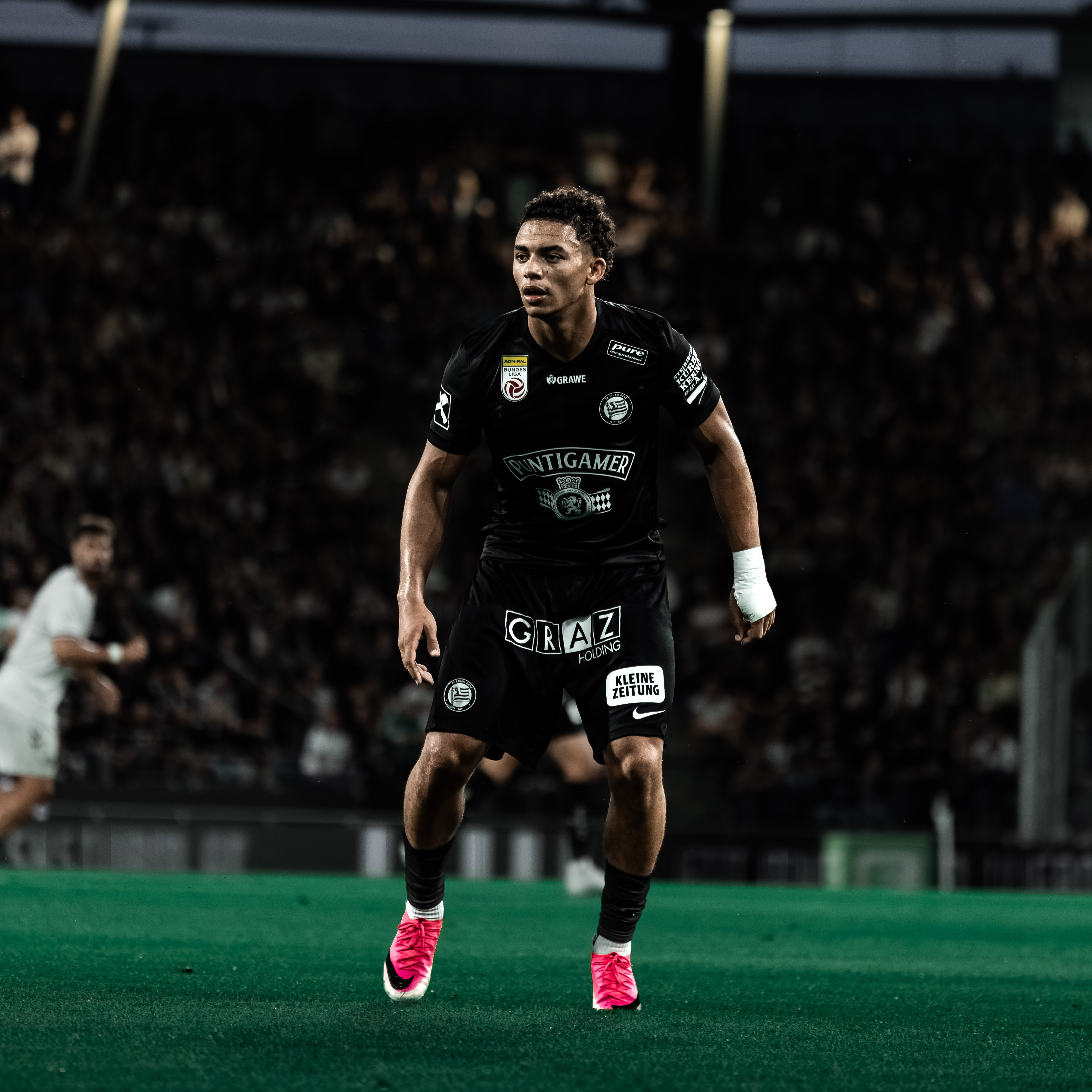 Ein Spieler in einem schwarzen Trikot steht und schaut in die Ferne.