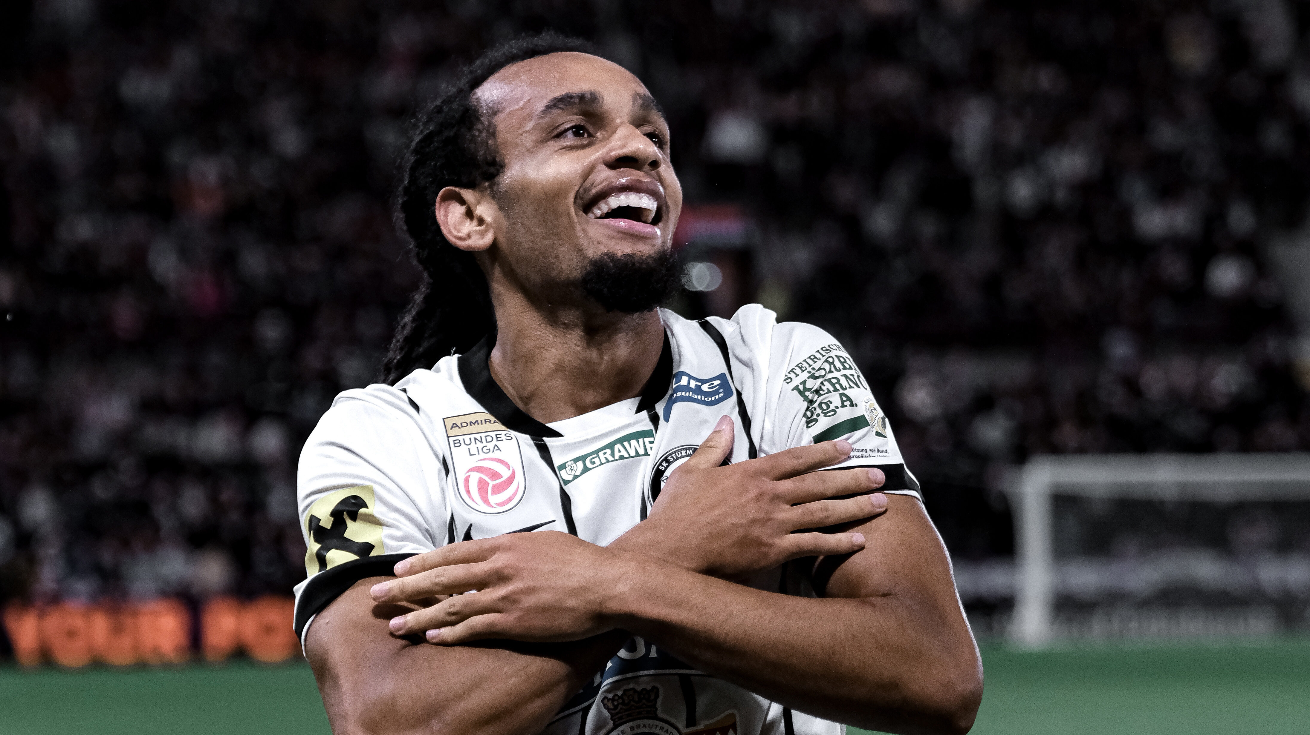 Ein Spieler in einem weißen Trikot hat die Arme verschränkt und jubelt.