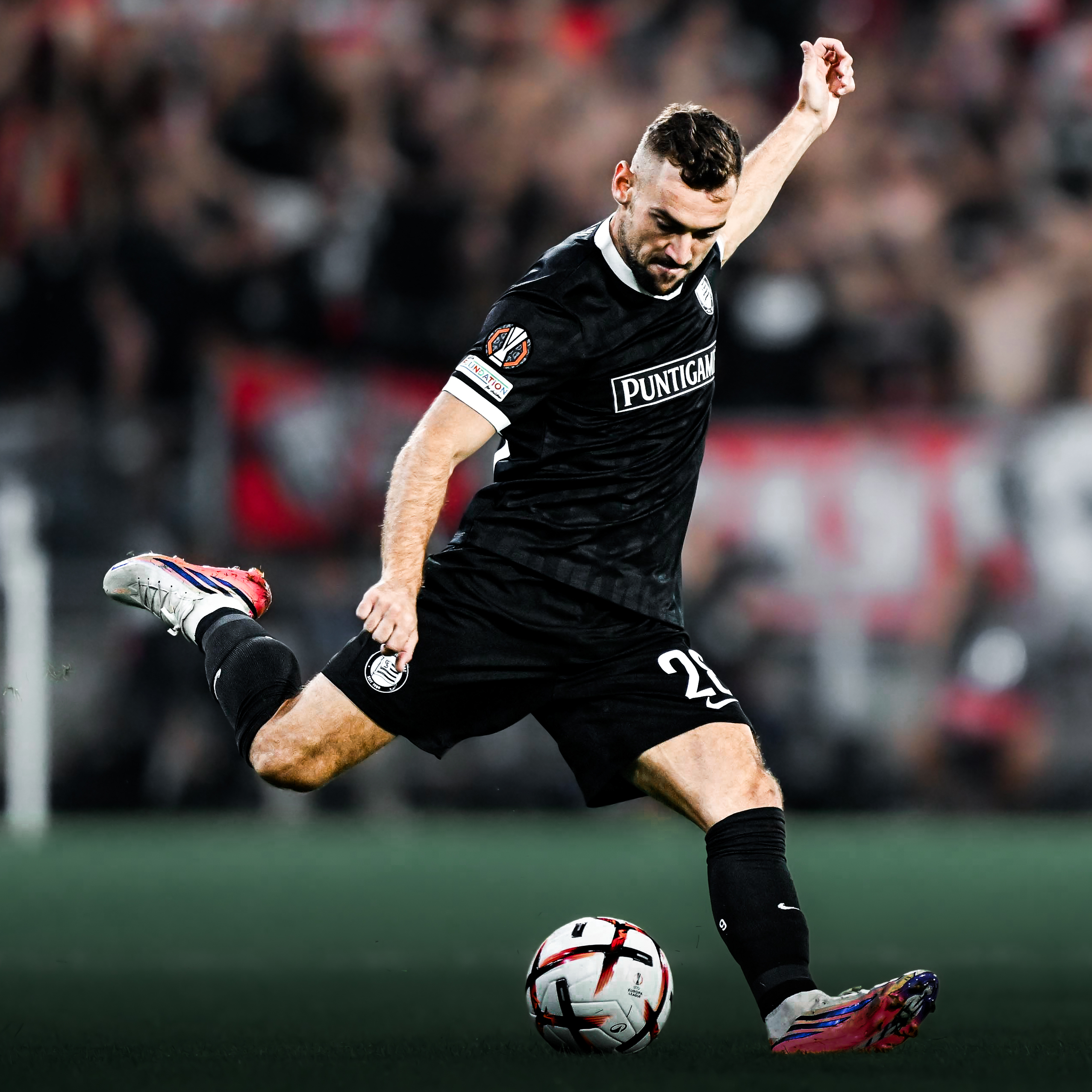 Ein Spieler in schwarz schießt einen weißen Ball nach rechts.
