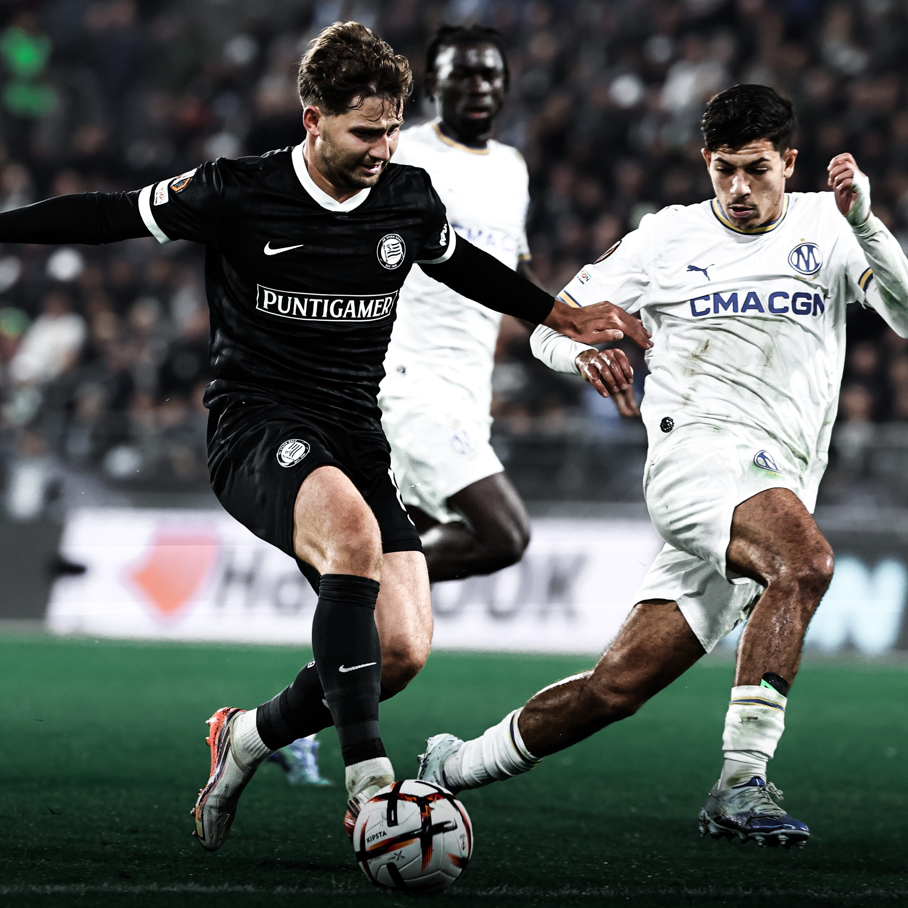 Ein Spieler in einem schwarzen Trikot kämpft mit einem in einem weißen um einen weißen Ball.