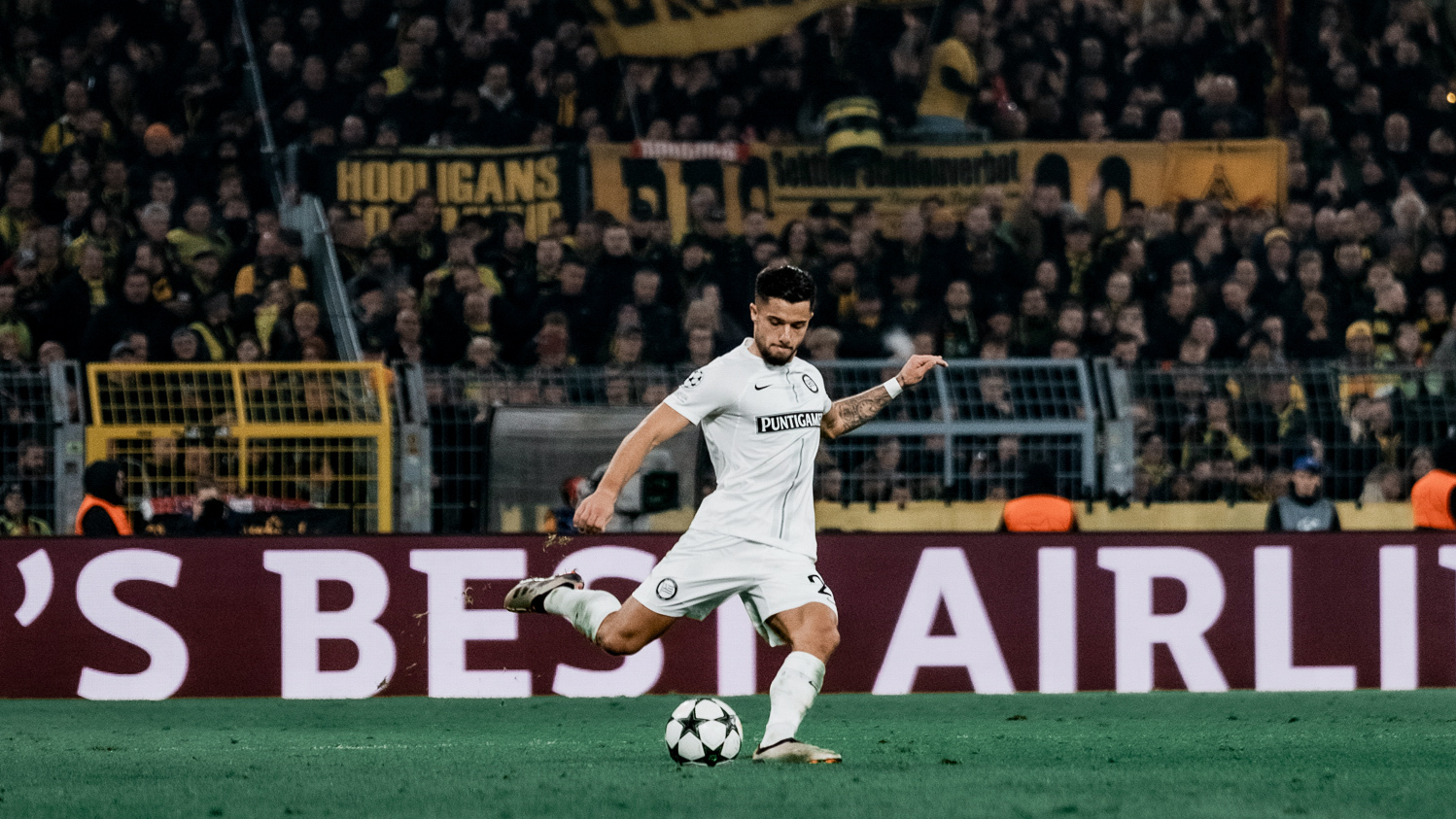 Fußballer in weißem Trikot schießt einen Ball.