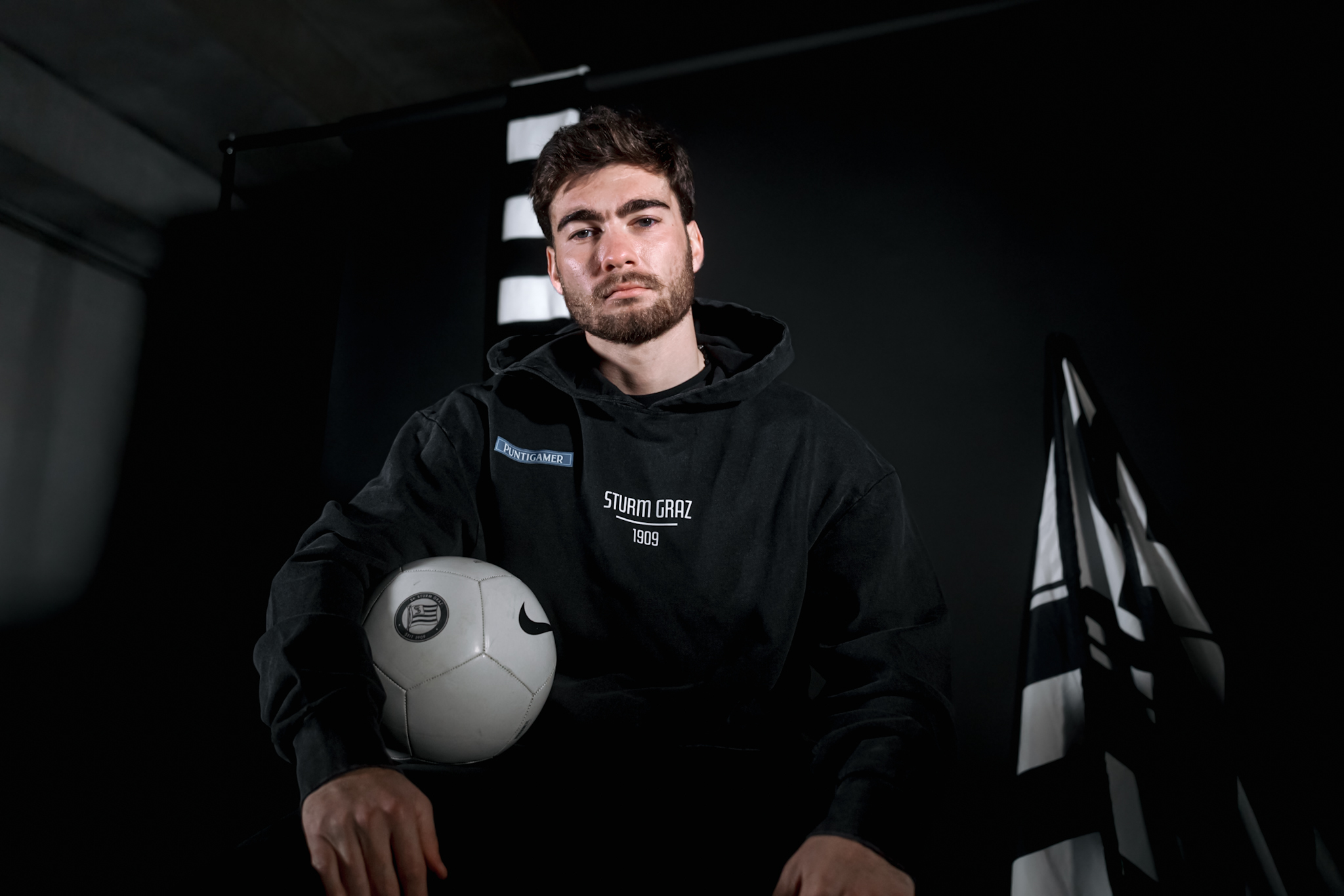 Mann mit Ball unter dem Arm in einer dunklen Garage.