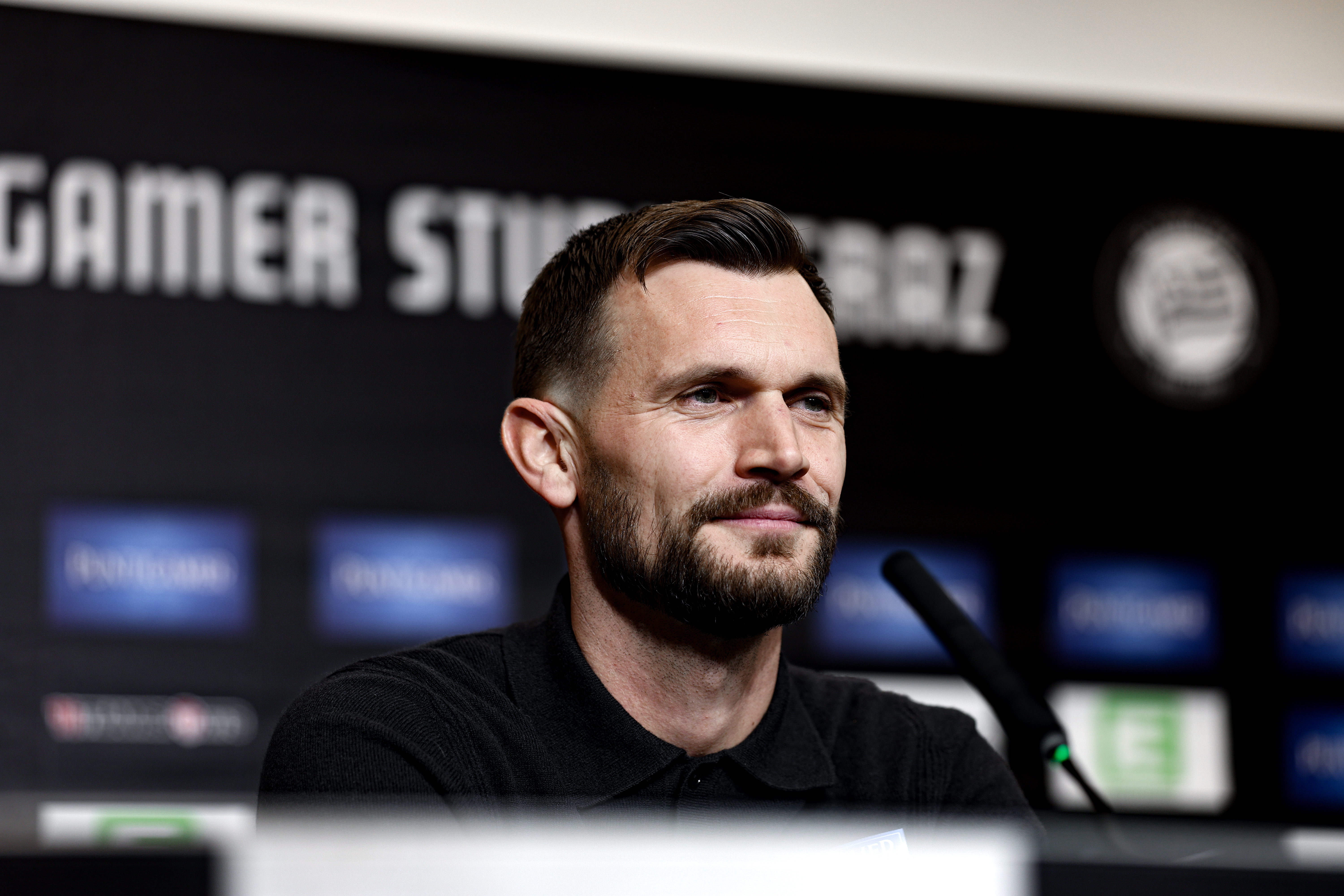 Ein Mann sitz vor einem Mikrofon