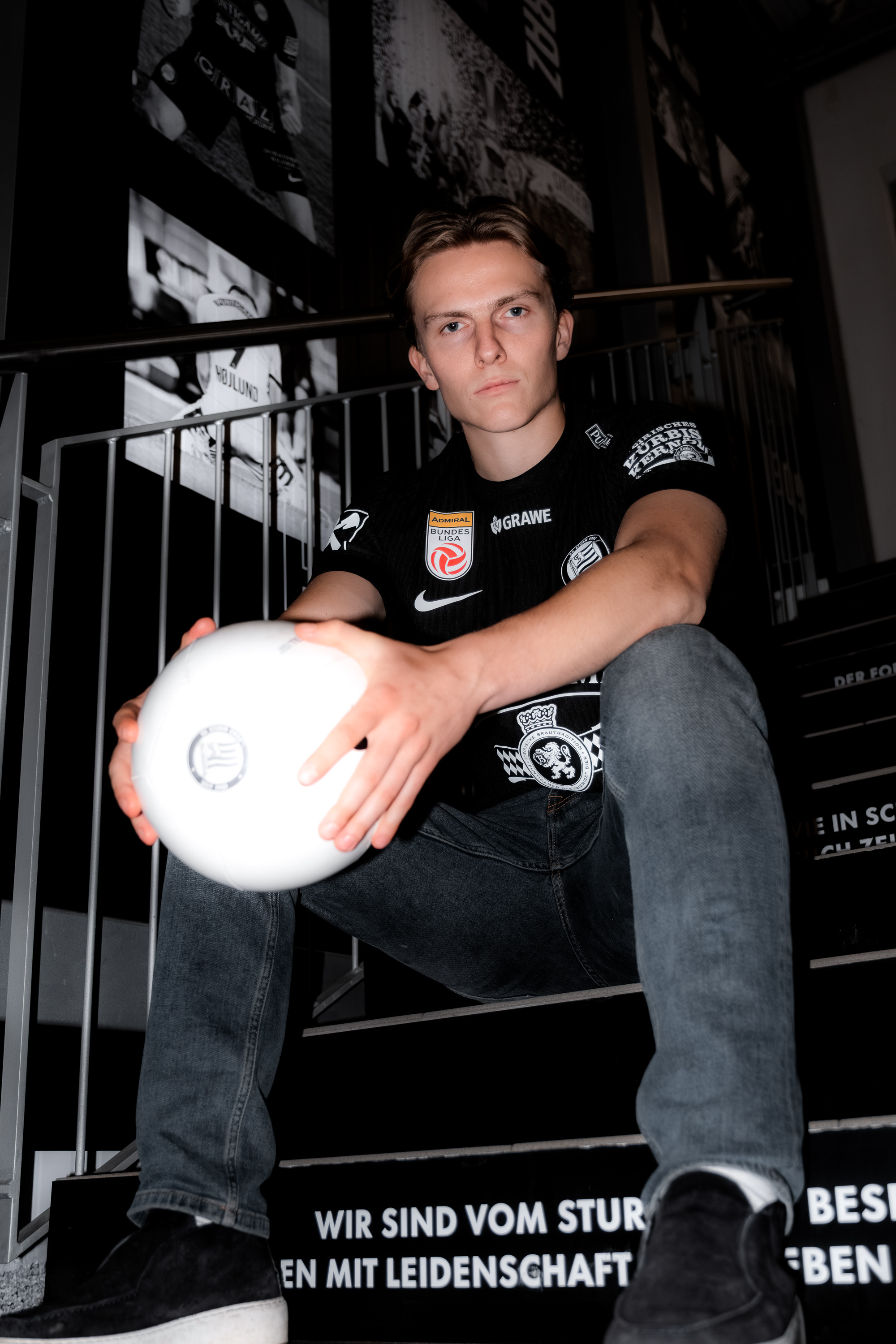 Eine Person sitzt mit einem Ball auf einer Stiege