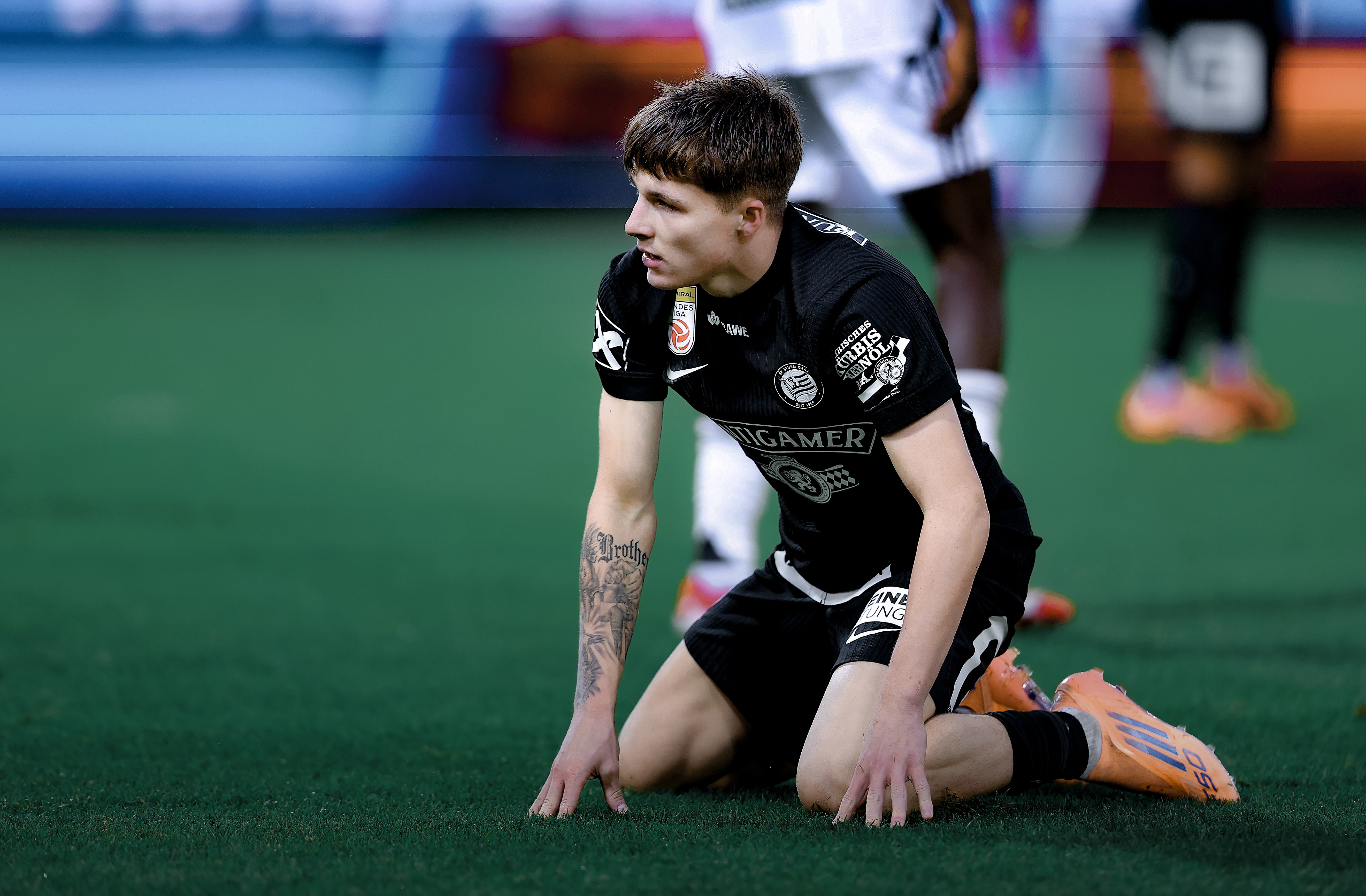 Ein Spieler in einem schwarzen Trikot und einer schwarzen Hose liegt am Rasen.