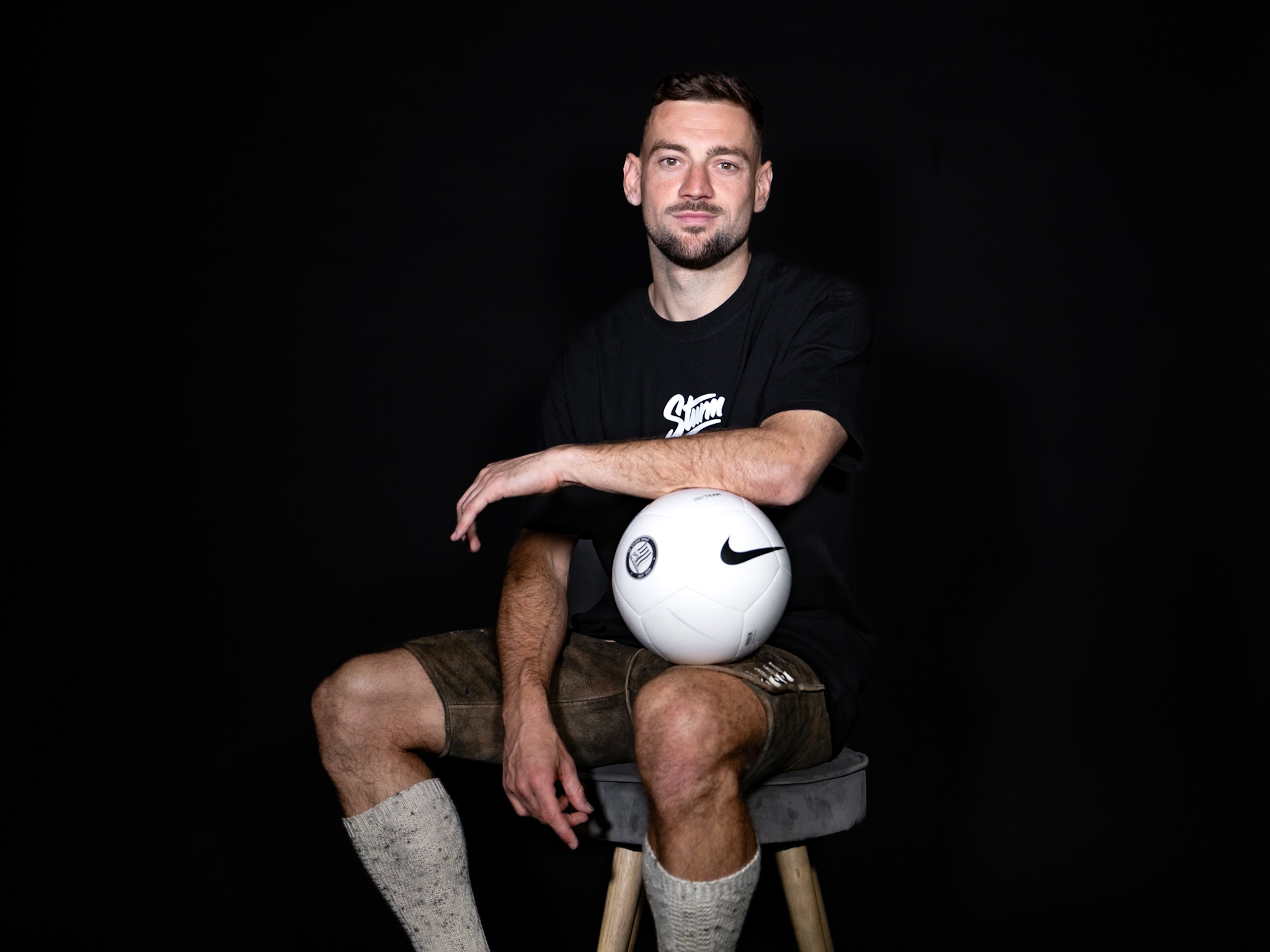 Mann in steirischer Tracht hält einen weißen Ball.