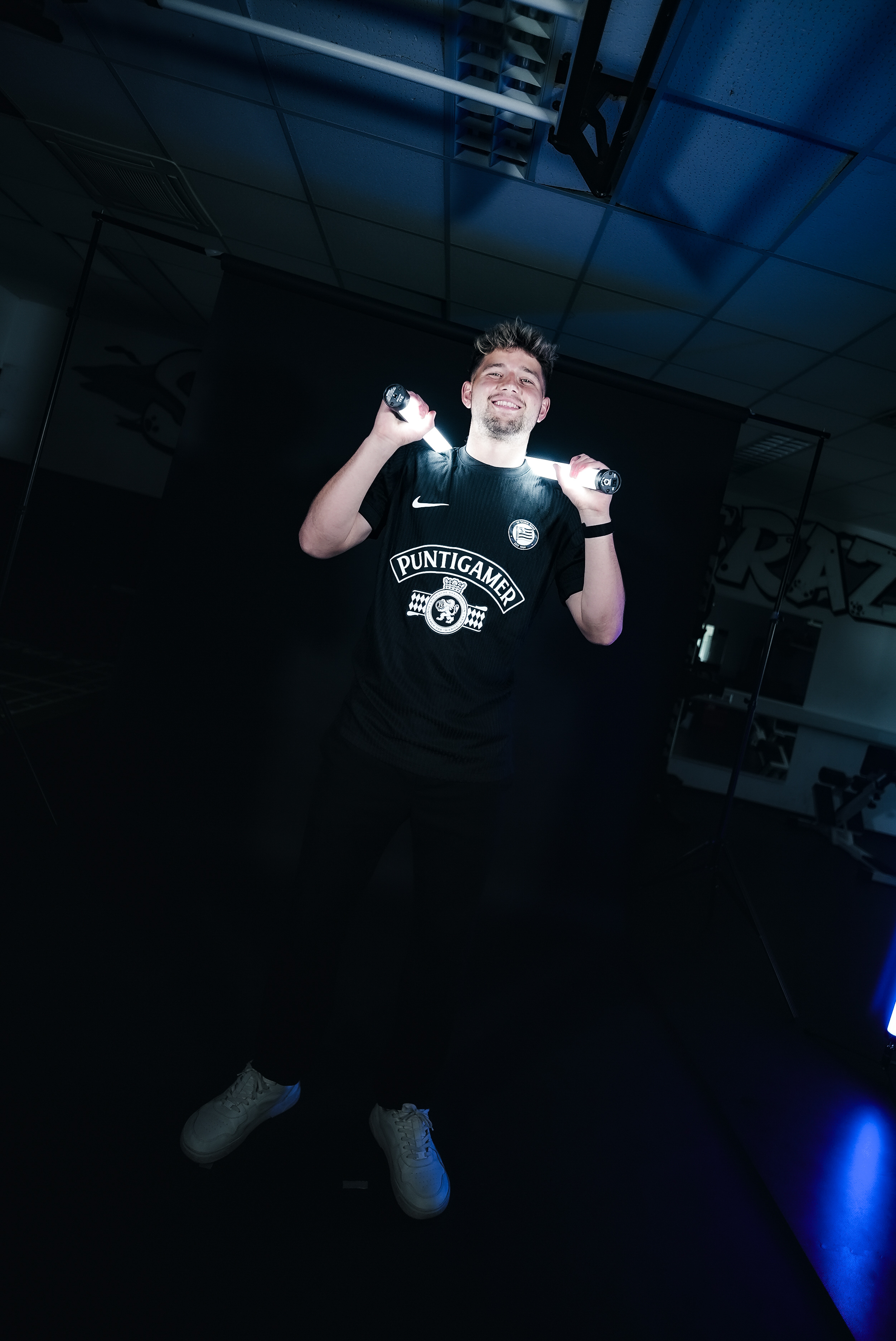 Mann steht in dunklem Raum mit einem Licht auf der Schulter.