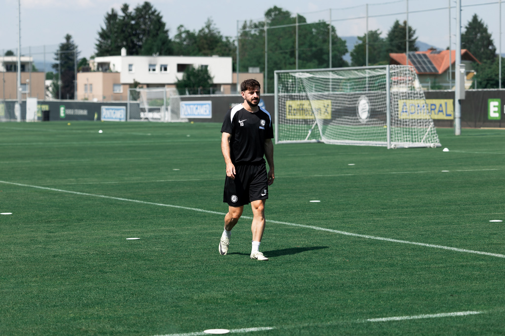 Ein Mann geht auf einem Fußballplatz.