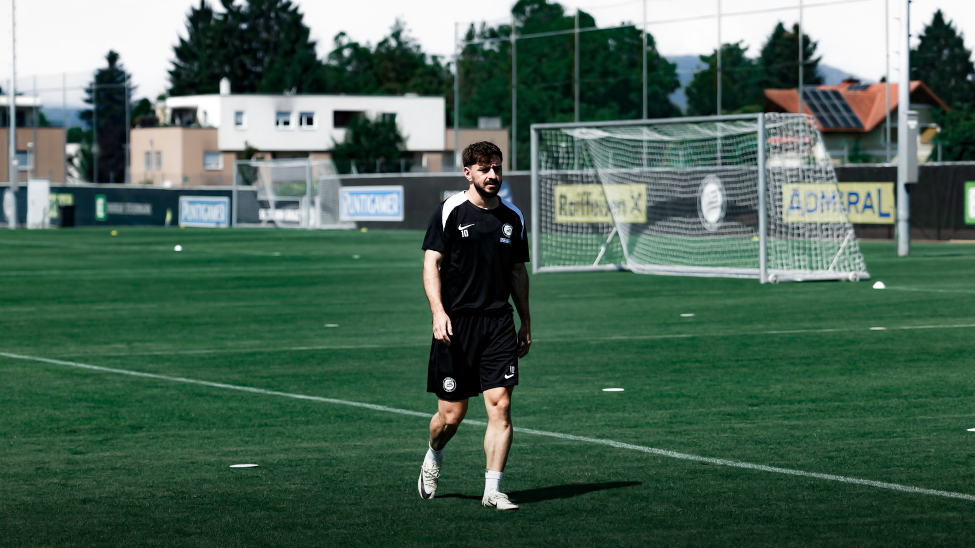 Ein Mann geht auf einem Fußballplatz.