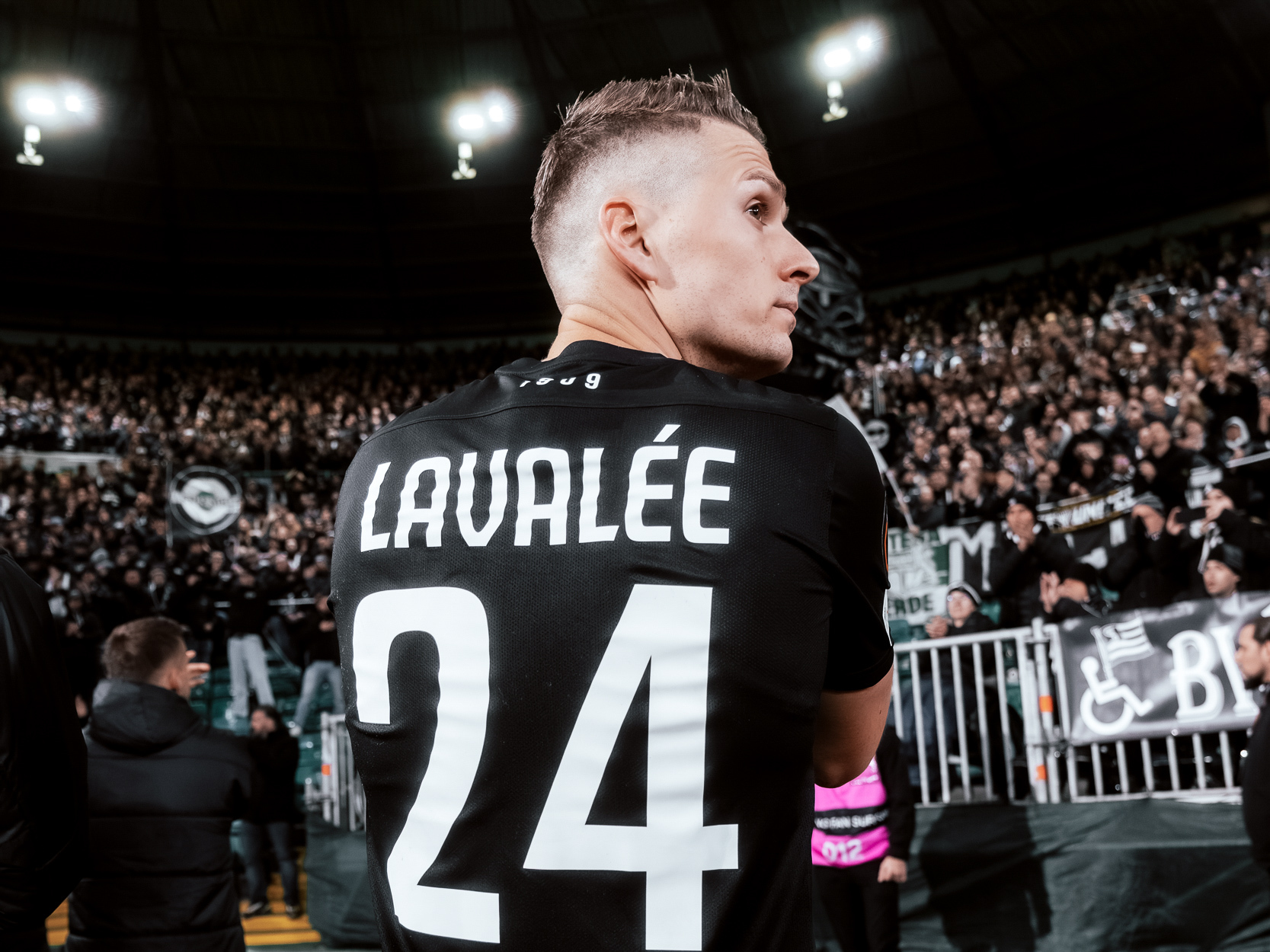 Eine Fußballspieler steht vor den Fans und bedankt sich.