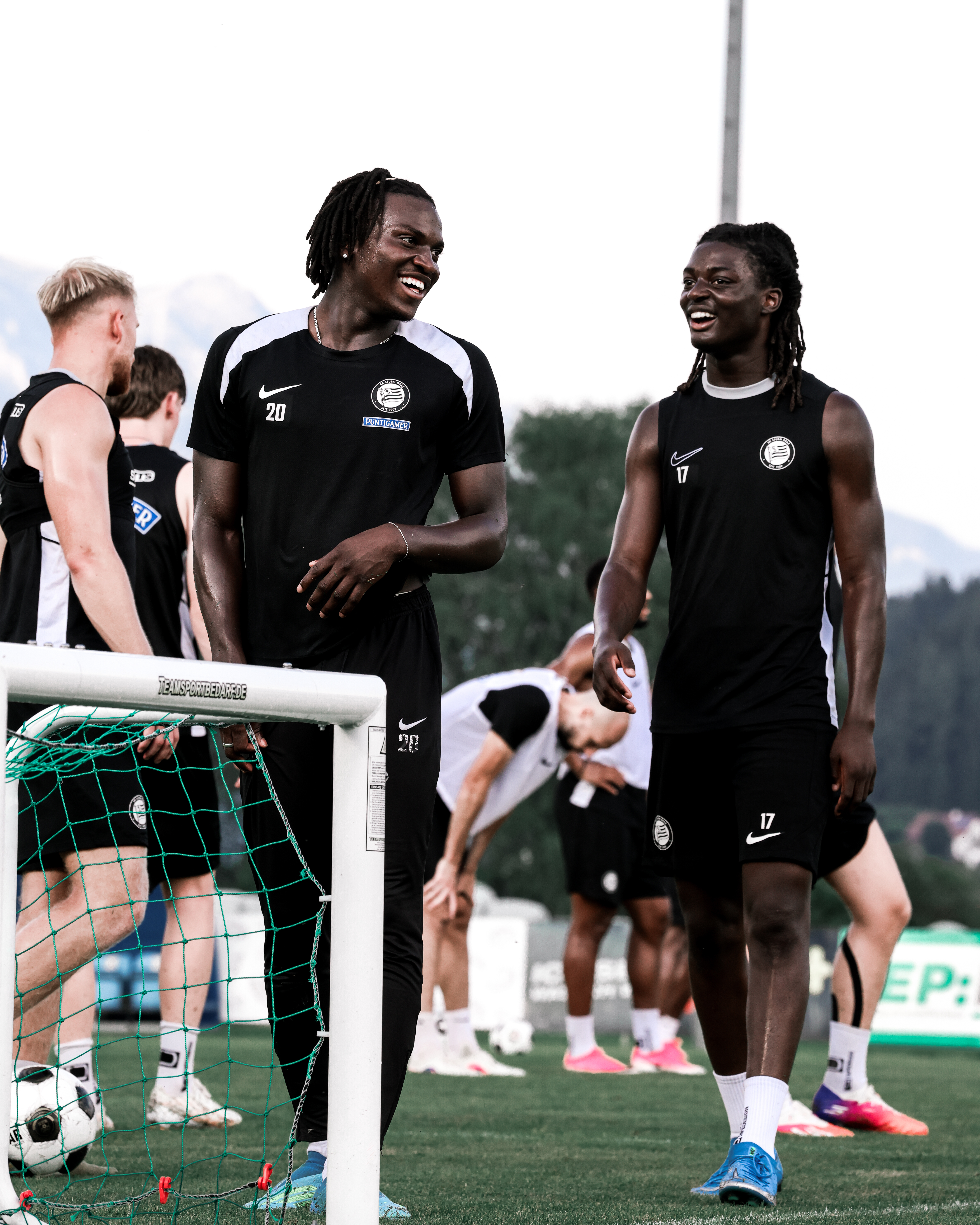 Zwei junge Männer stehen am Fußballplatz und lachen