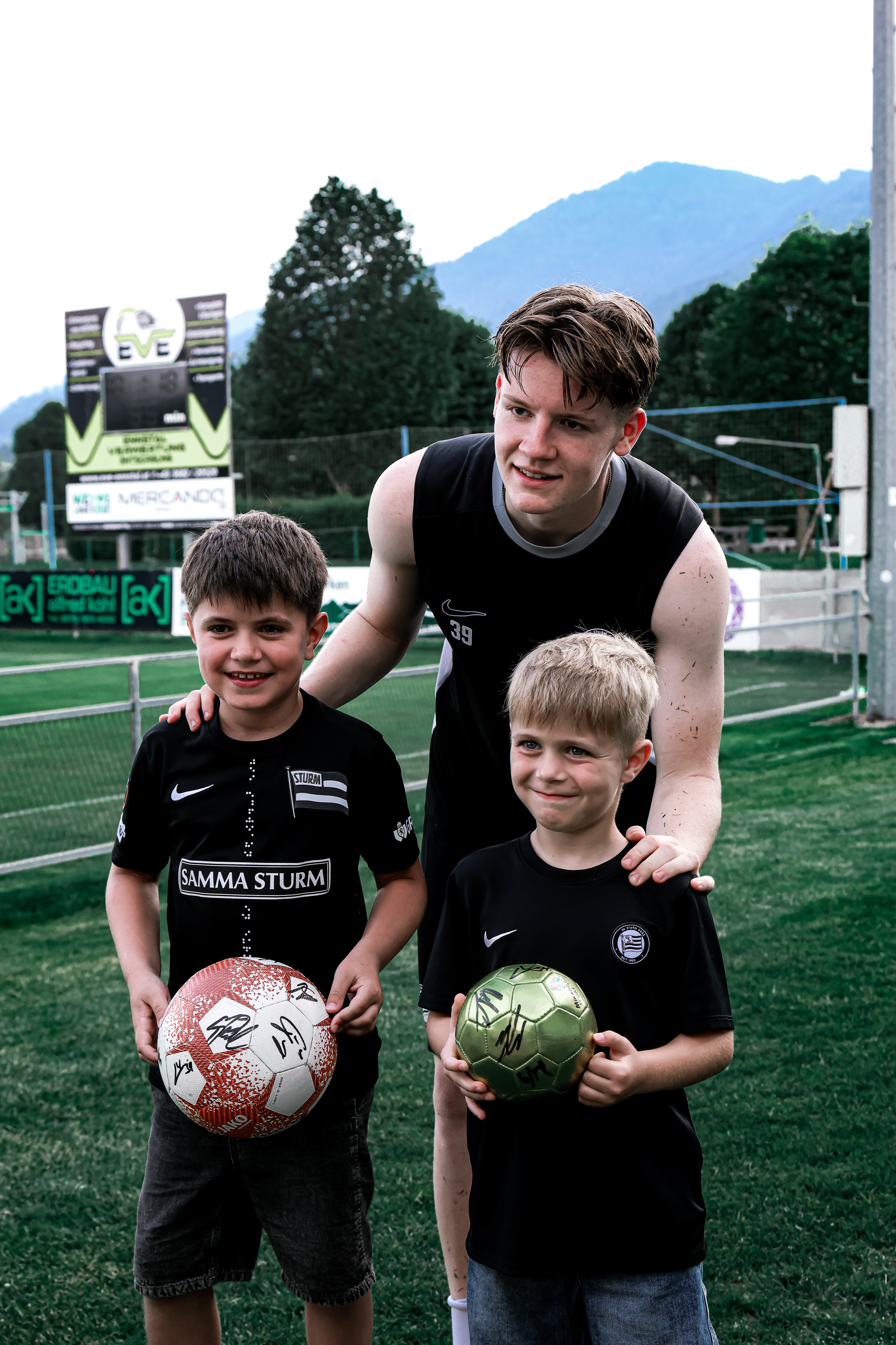 Junger Fußballer posiert mit zwei Kindern.