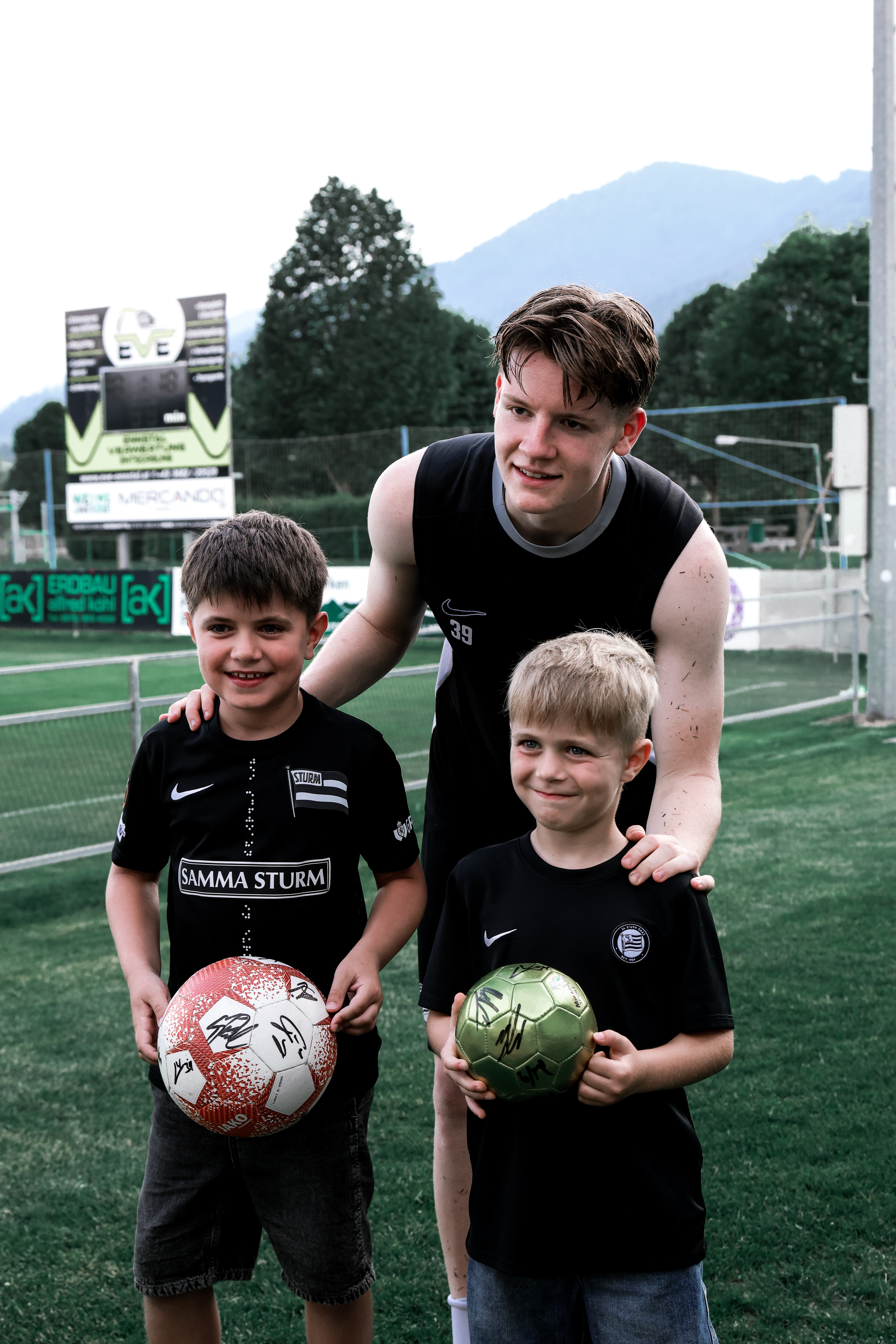 Junger Fußballer posiert mit zwei Kindern.