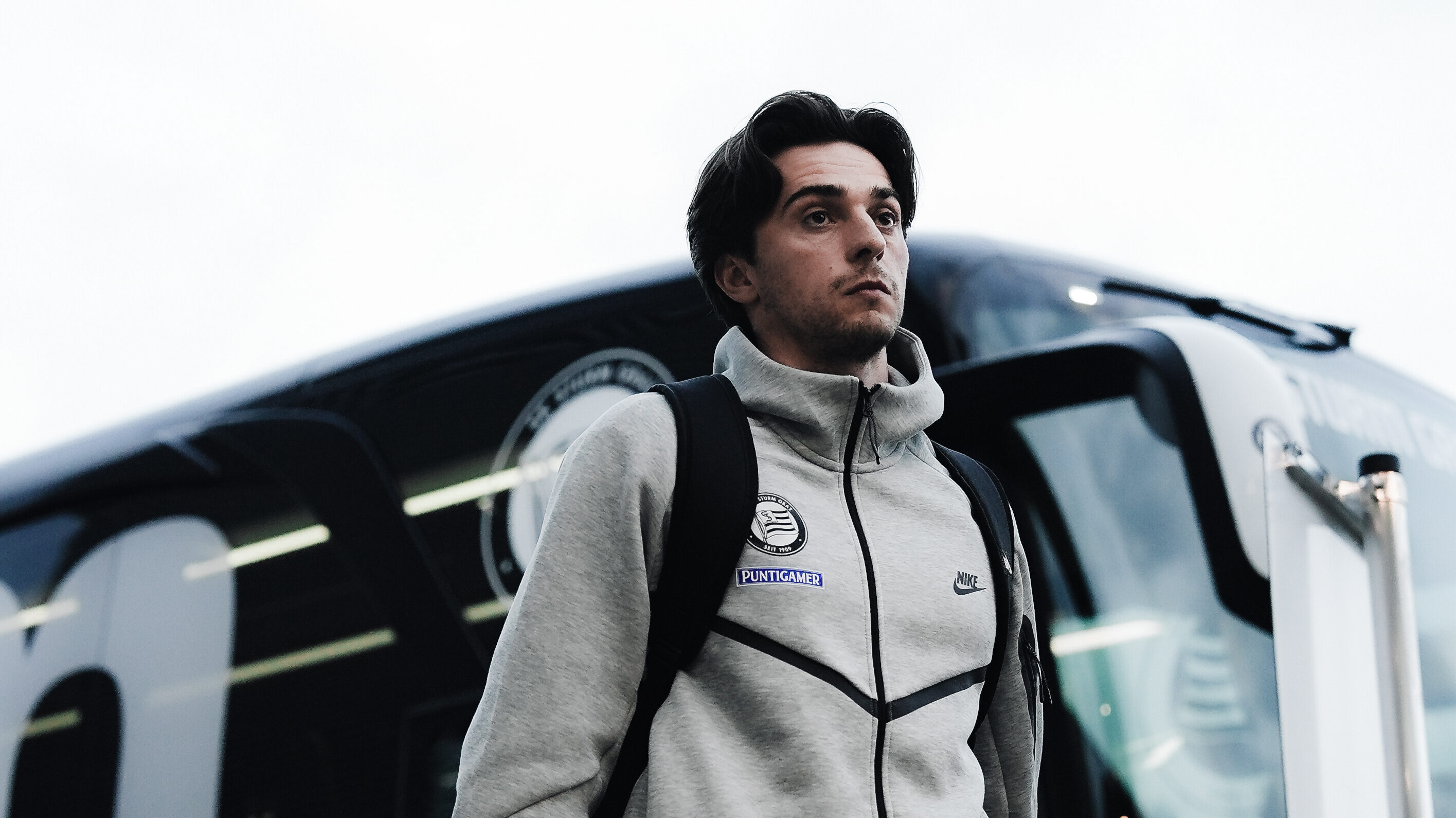 Ein Mann mit Trainingsanzug geht an einem Bus vorbei.