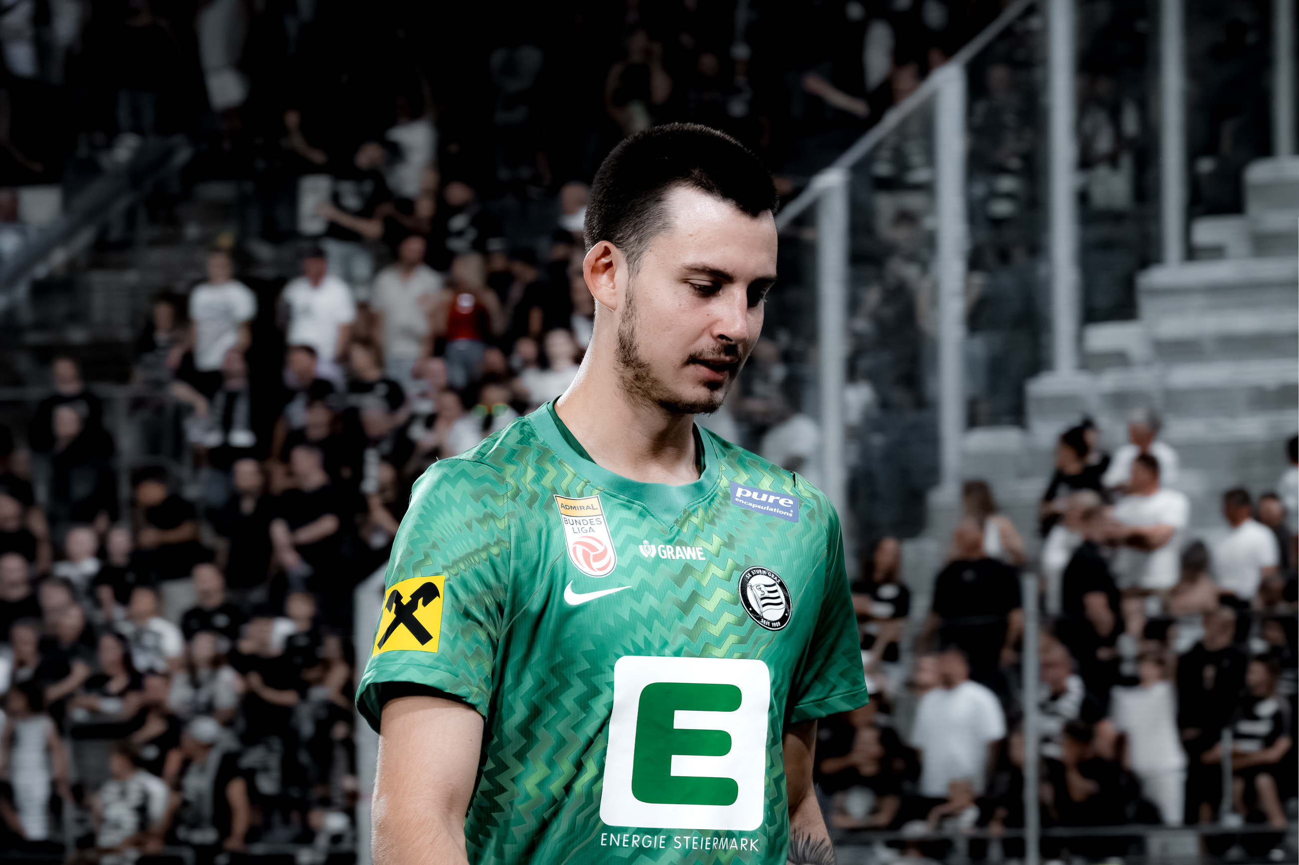 Mann in grünem Shirt geht mit gesenktem Kopf.