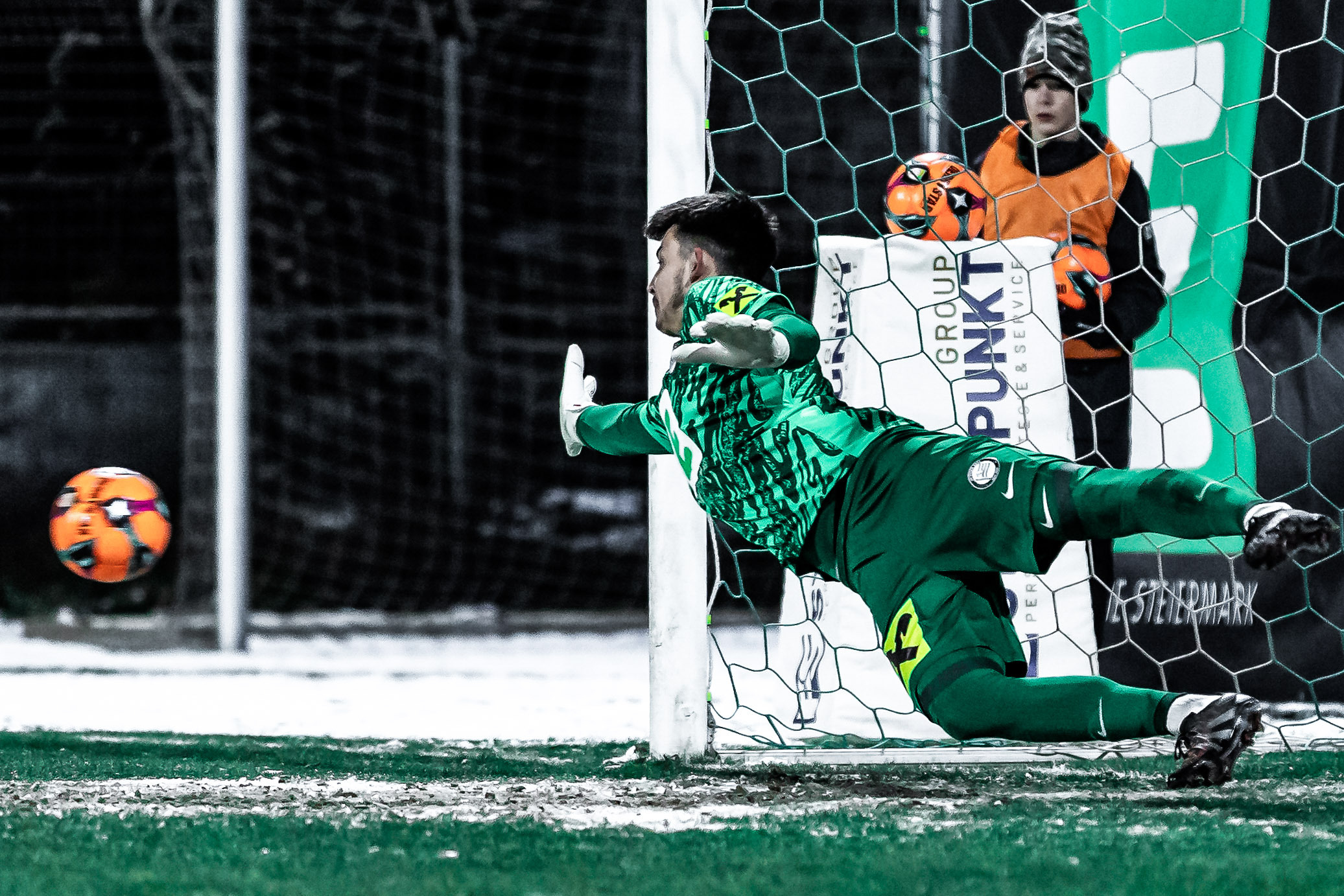 Ein Mann im grünen Trikot der zu einem Ball springt