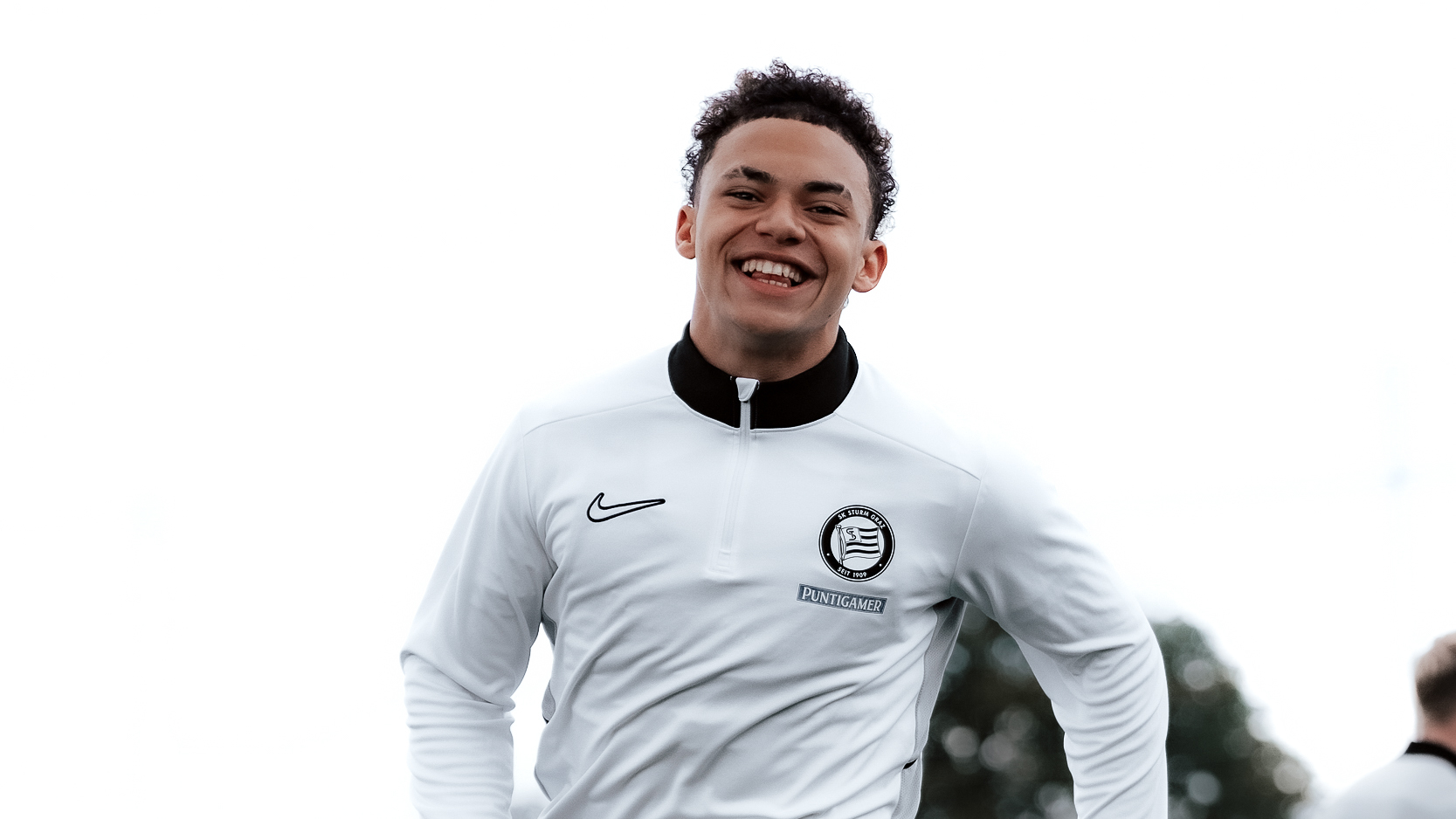 Ein Spieler lacht und hat ein weißes langes Trainingsshirt an