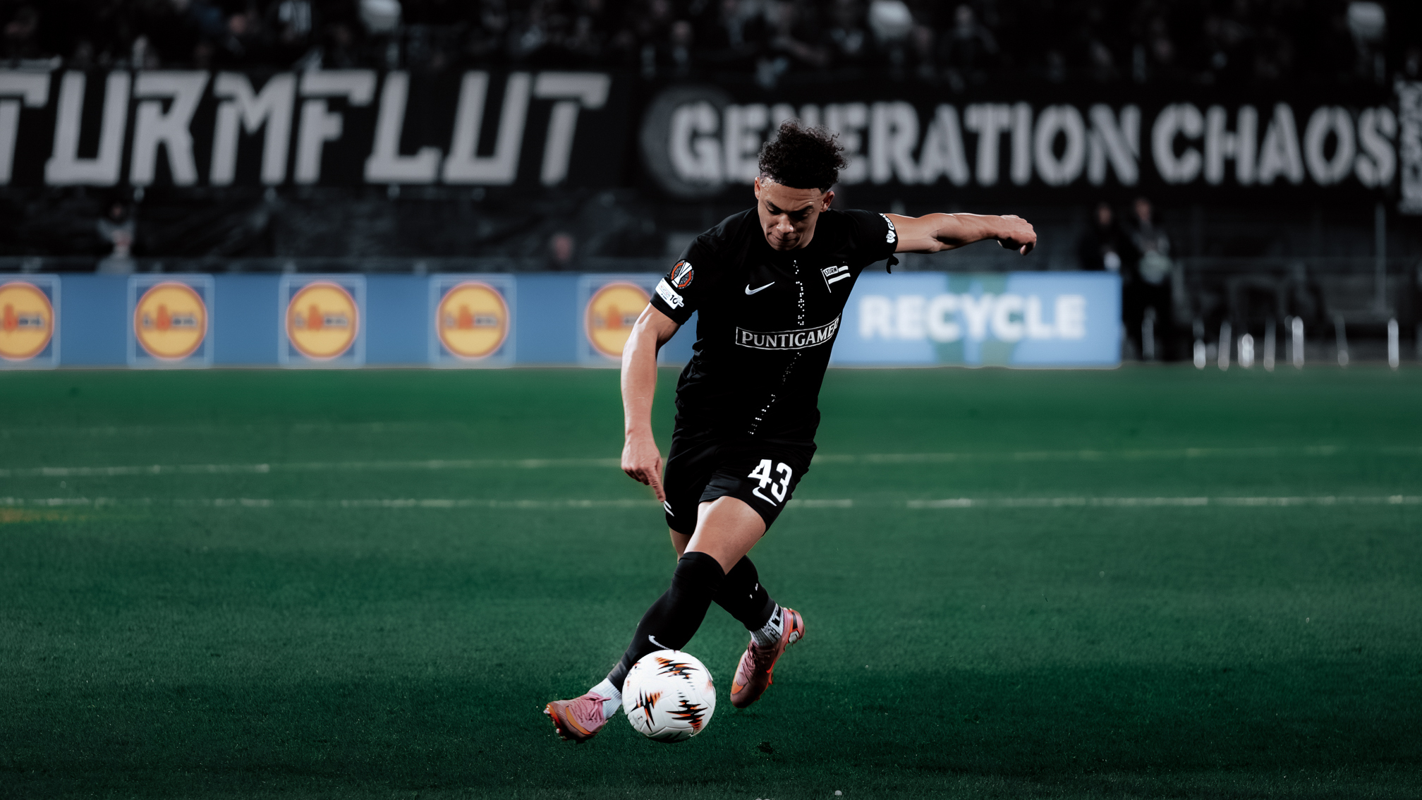 Ein Spieler in einem schwarzen Trikot dribbelt mit einem weißen Ball.