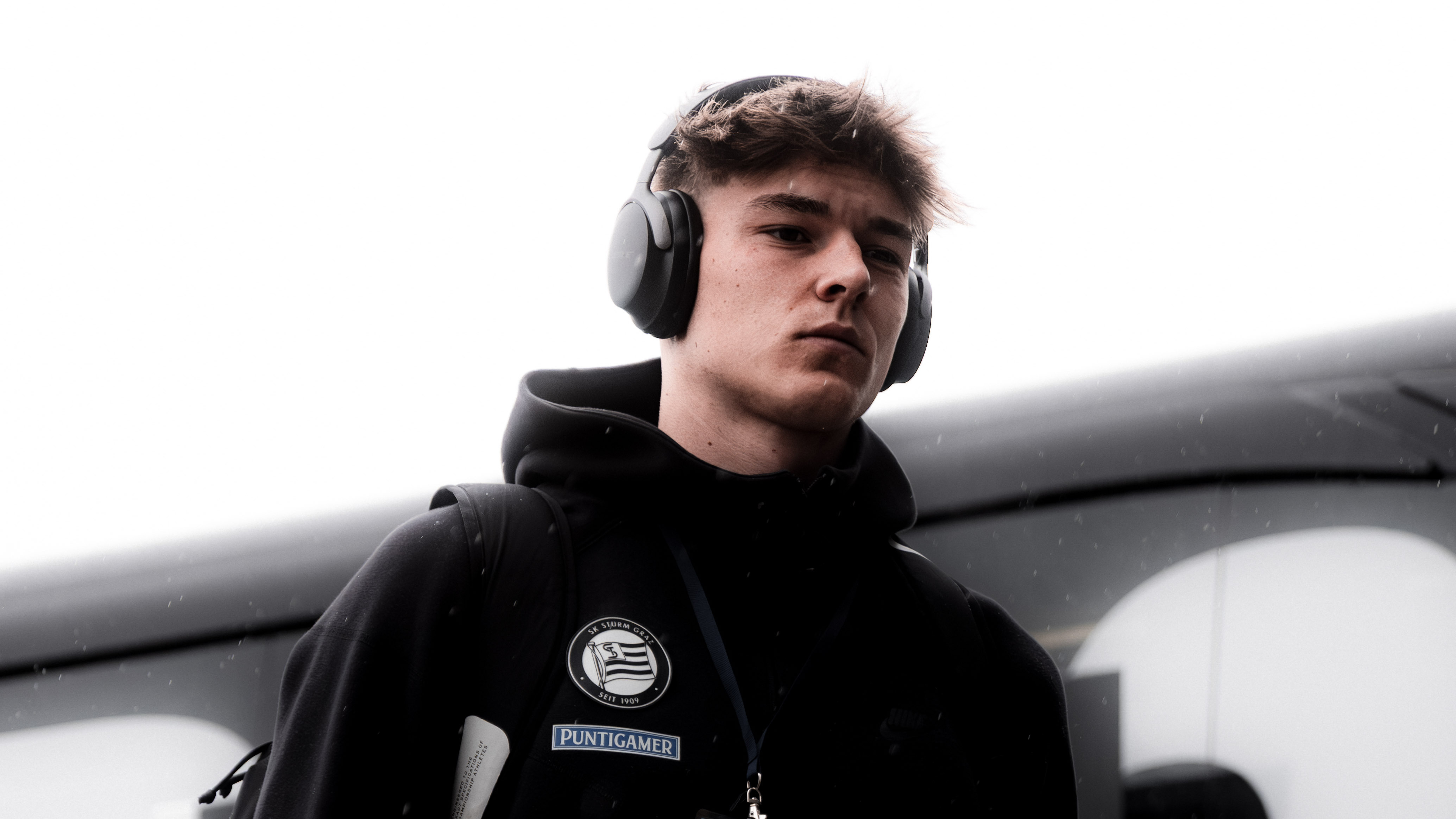 Ein Mann in einer schwarzen Weste und Kopfhörern schaut auf den Boden