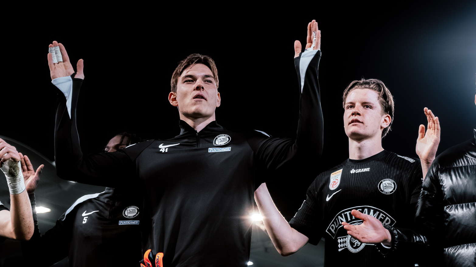 Zwei Spieler in schwarz halten ihre Hände hoch