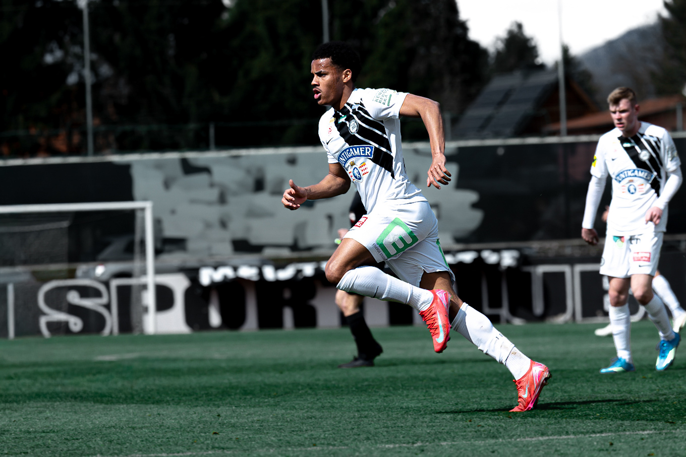 Spieler in weißem Trikot läuft dynamisch über das Feld.