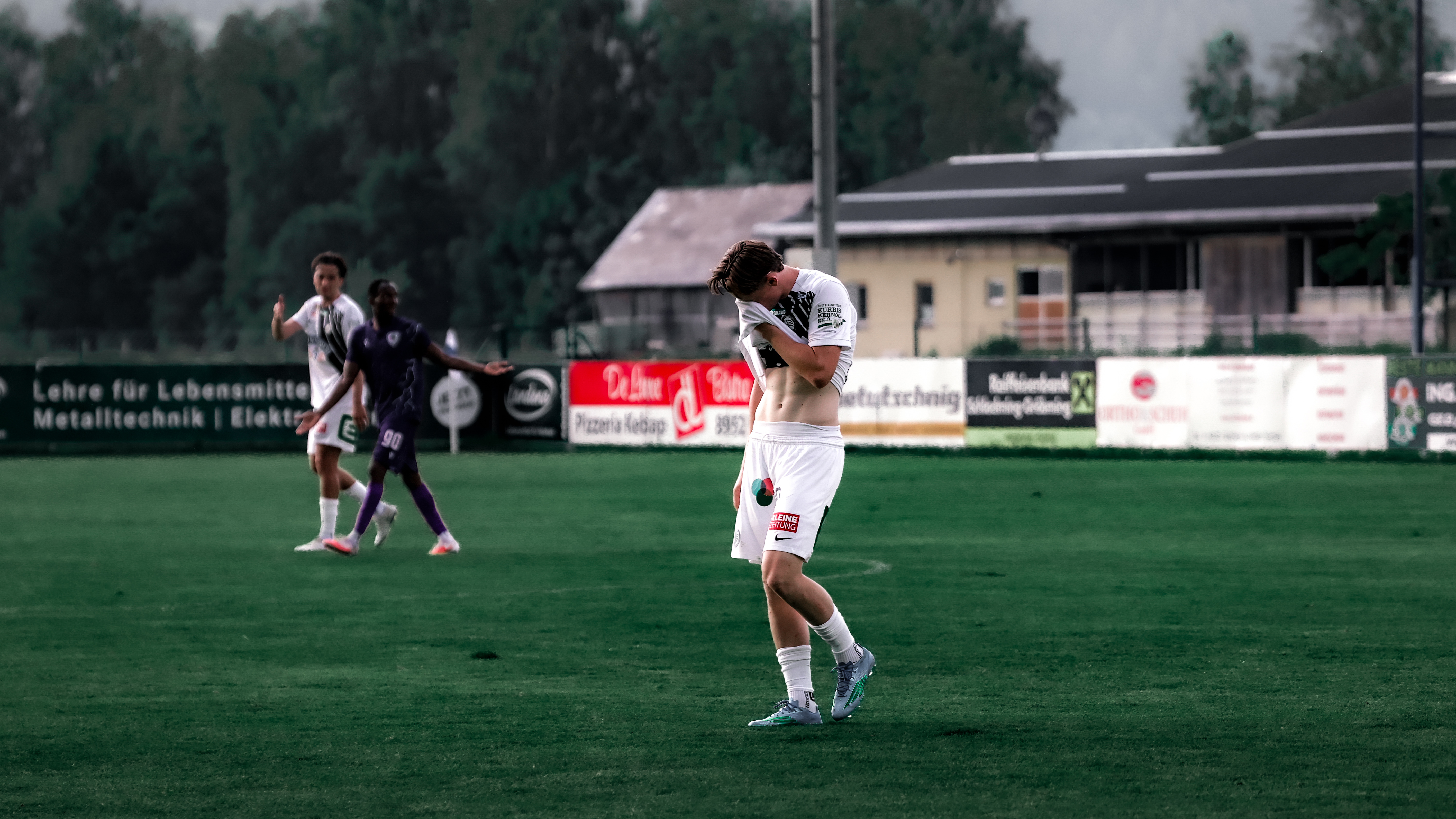 Junger Mann mit hängendem Kopf am Fußballfeld.
