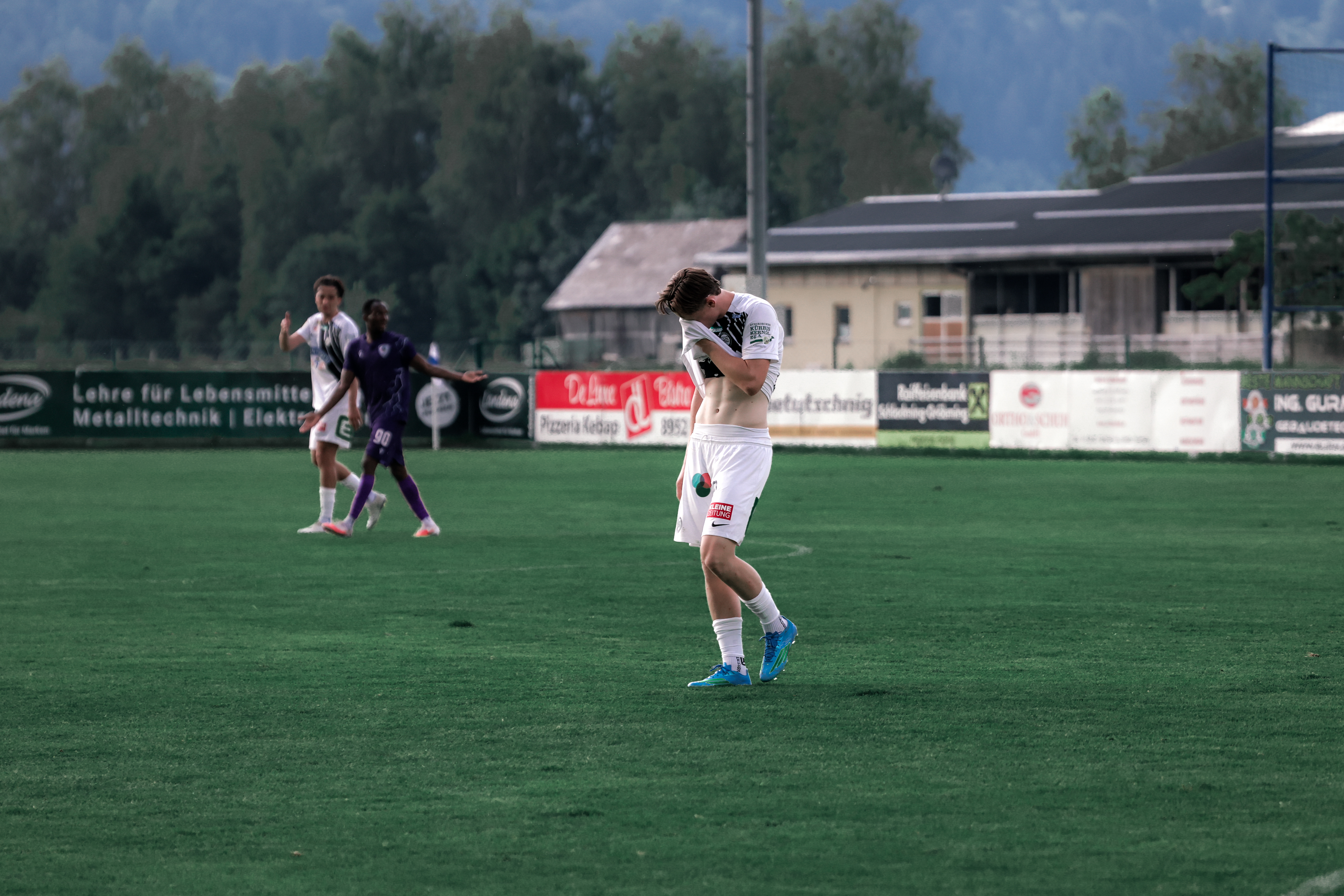 Junger Mann mit hängendem Kopf am Fußballfeld.