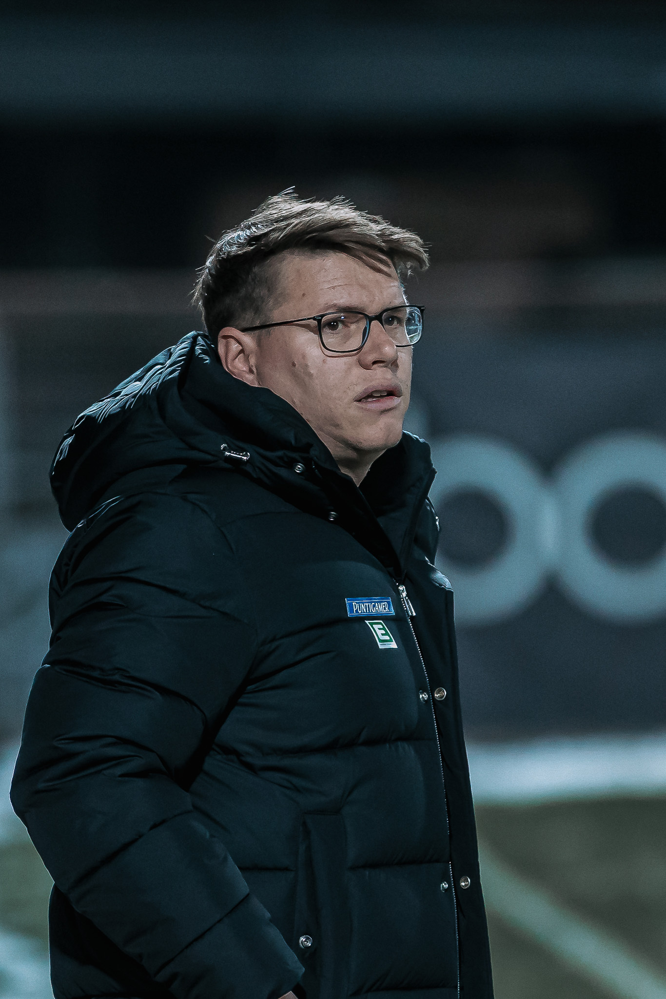 En Mann in warmer Jacke schaut in die Gegend.