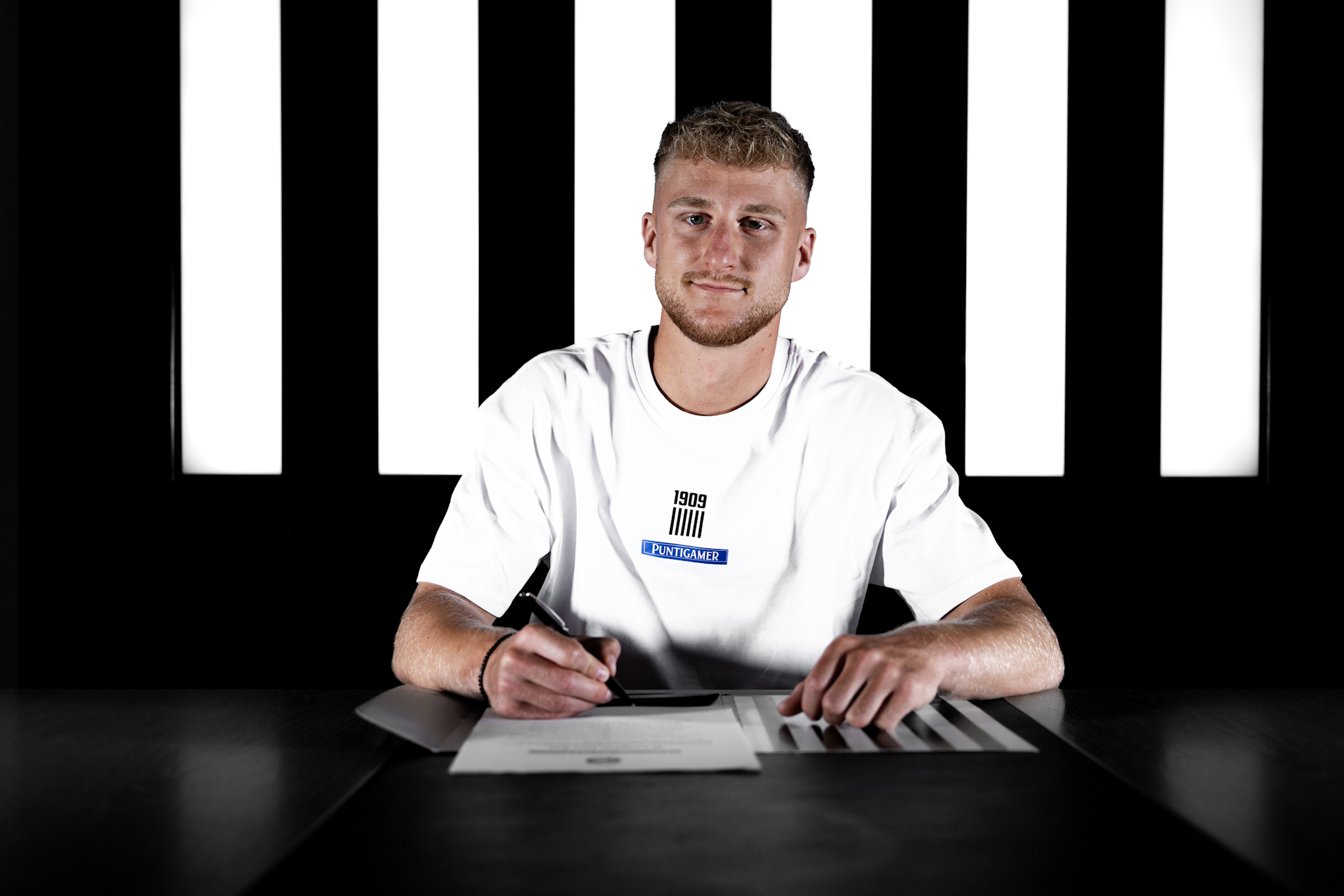 Mann in weißem Shirt unterschreibt einen Vertrag.