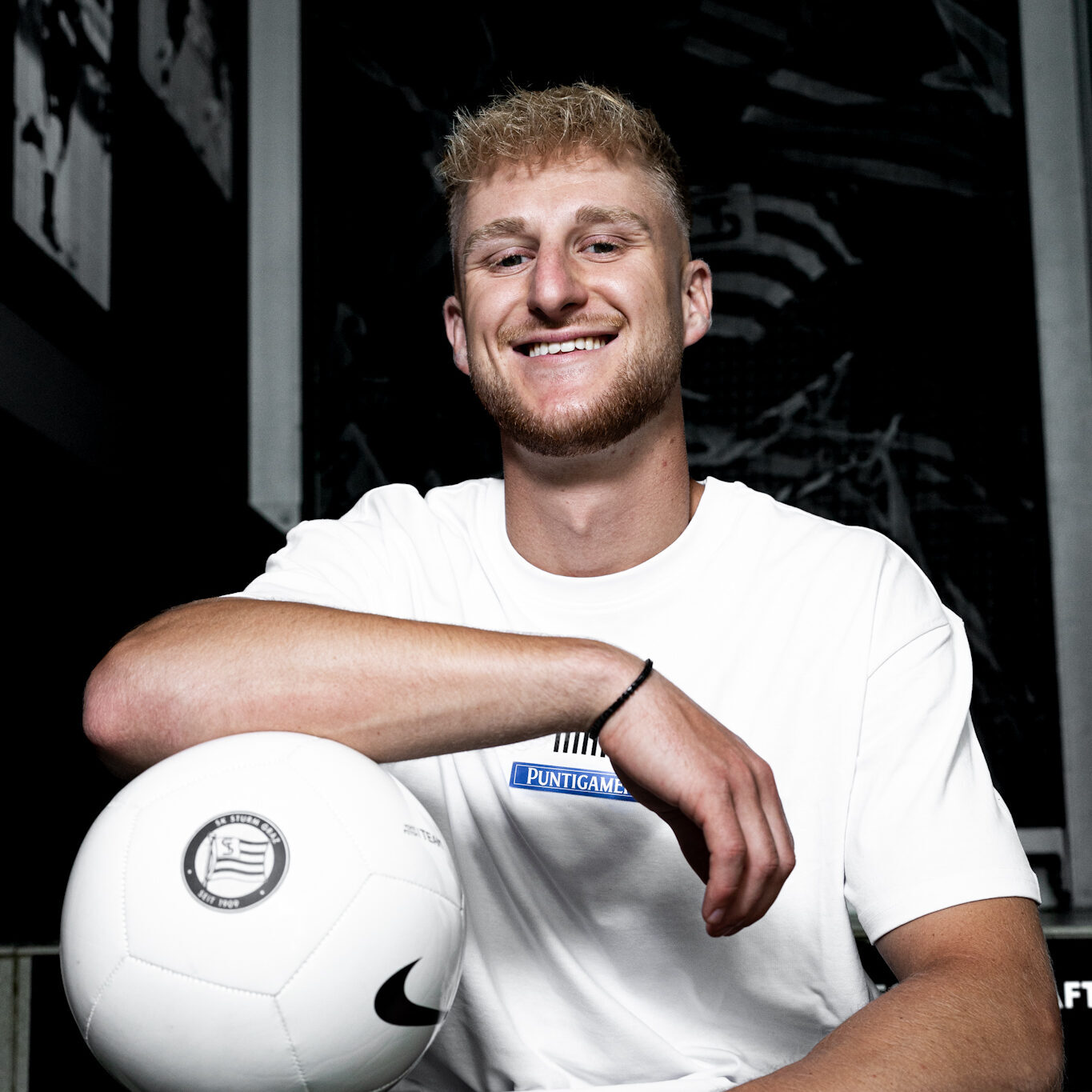 Mann sitzt auf einer Stiege mit Ball unter dem Arm.