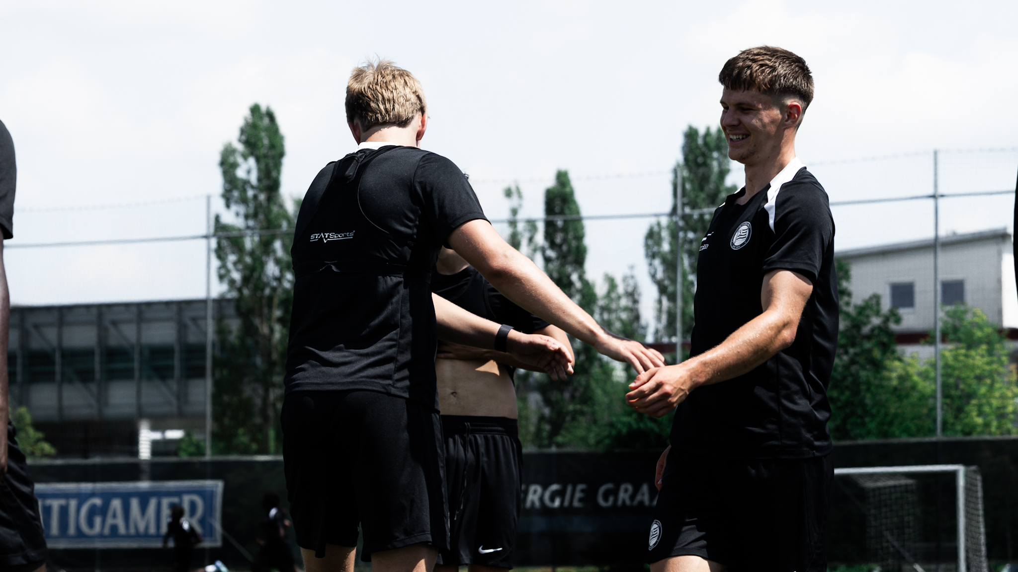 Zwei Spieler in einem schwarzen Trainingsshirt klatschen ab