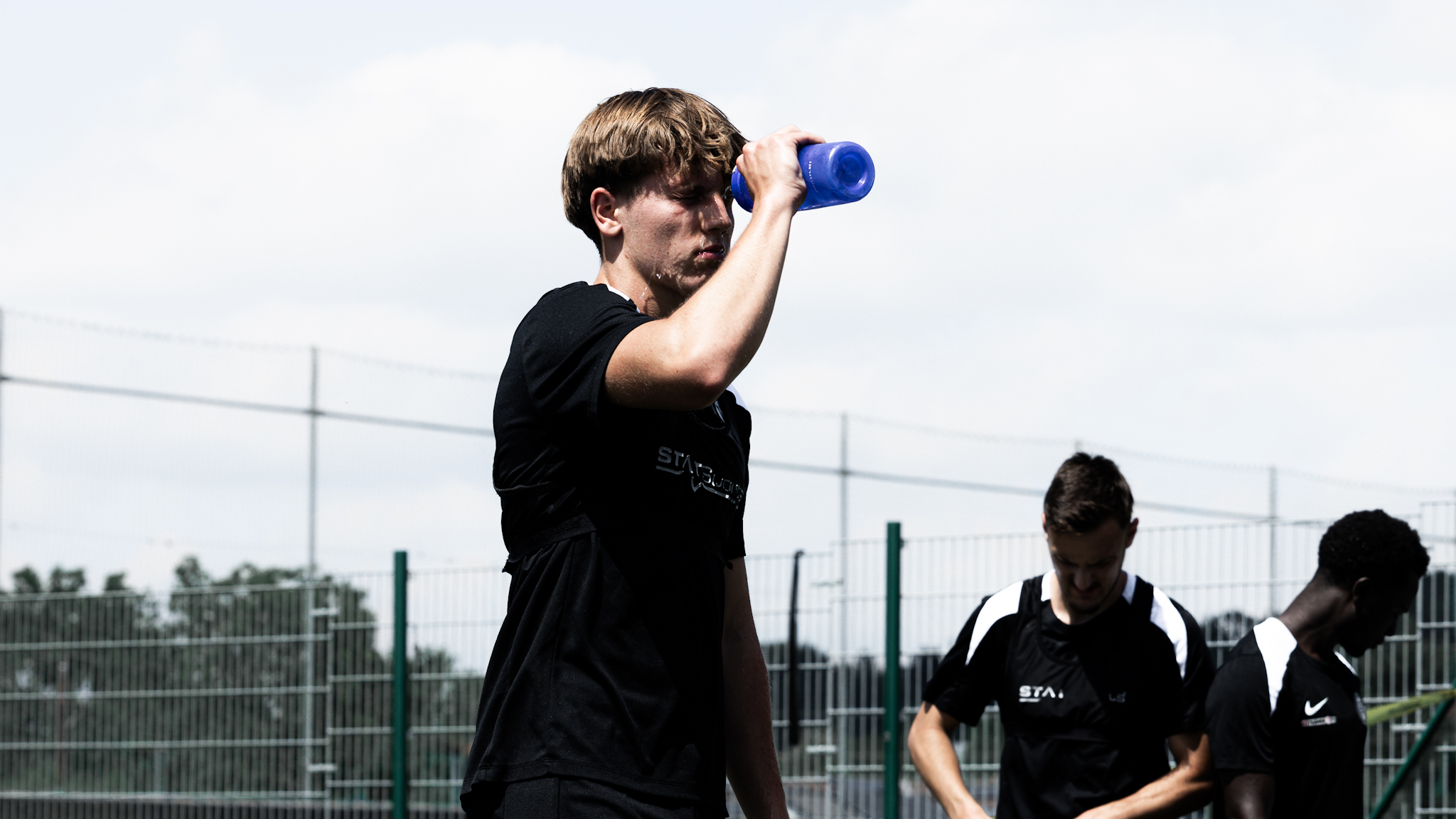 Ein Spieler in einem schwarzen Trainingsshirt spritzt sich Wasser ins Gesicht