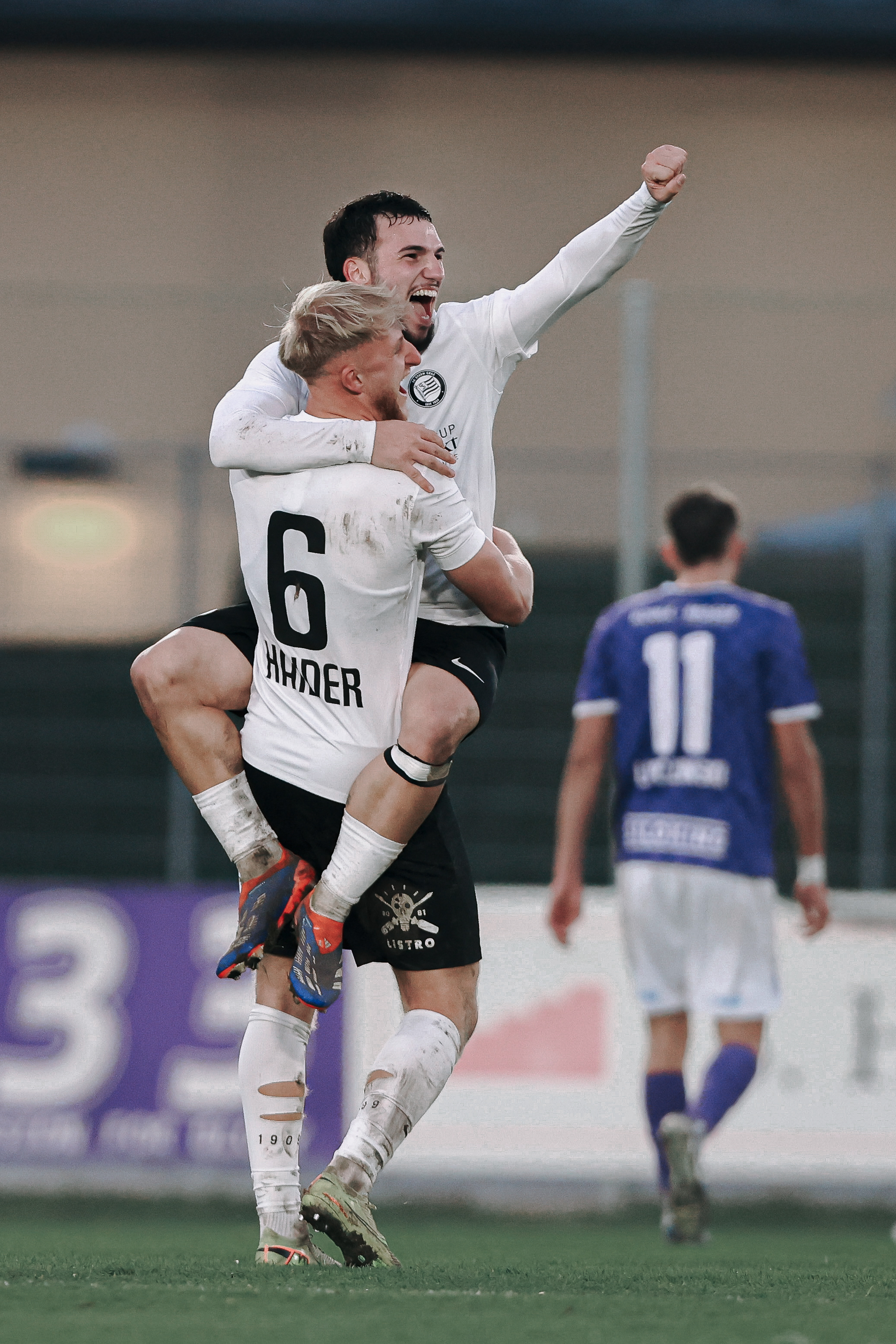 Zwei Männer umarmen sich und jubeln.