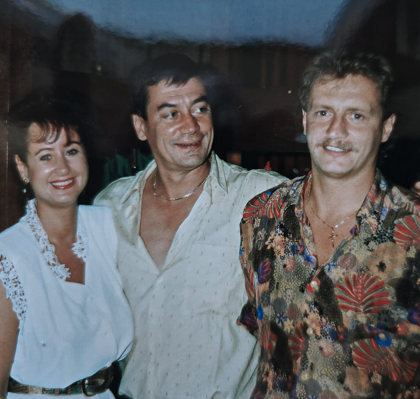 Zwei Männer und eine Frau Arm in Arm.