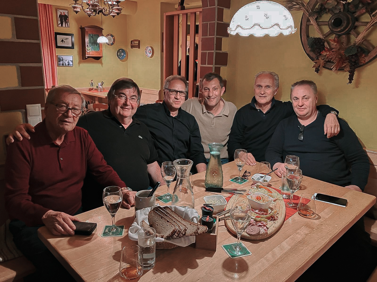 Sechs Herren sitzen an einem Tisch und feiern.