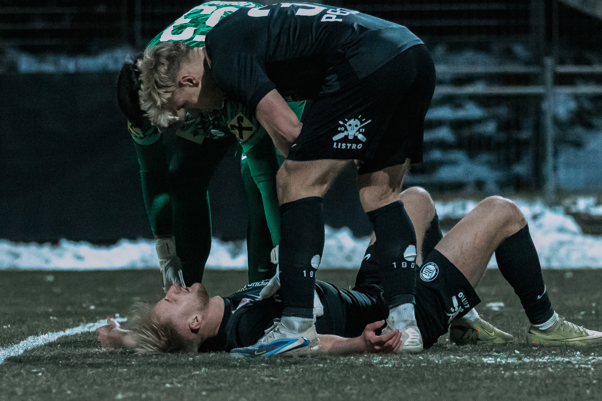 Zwei Fußballer, einer steht, einer liegt.