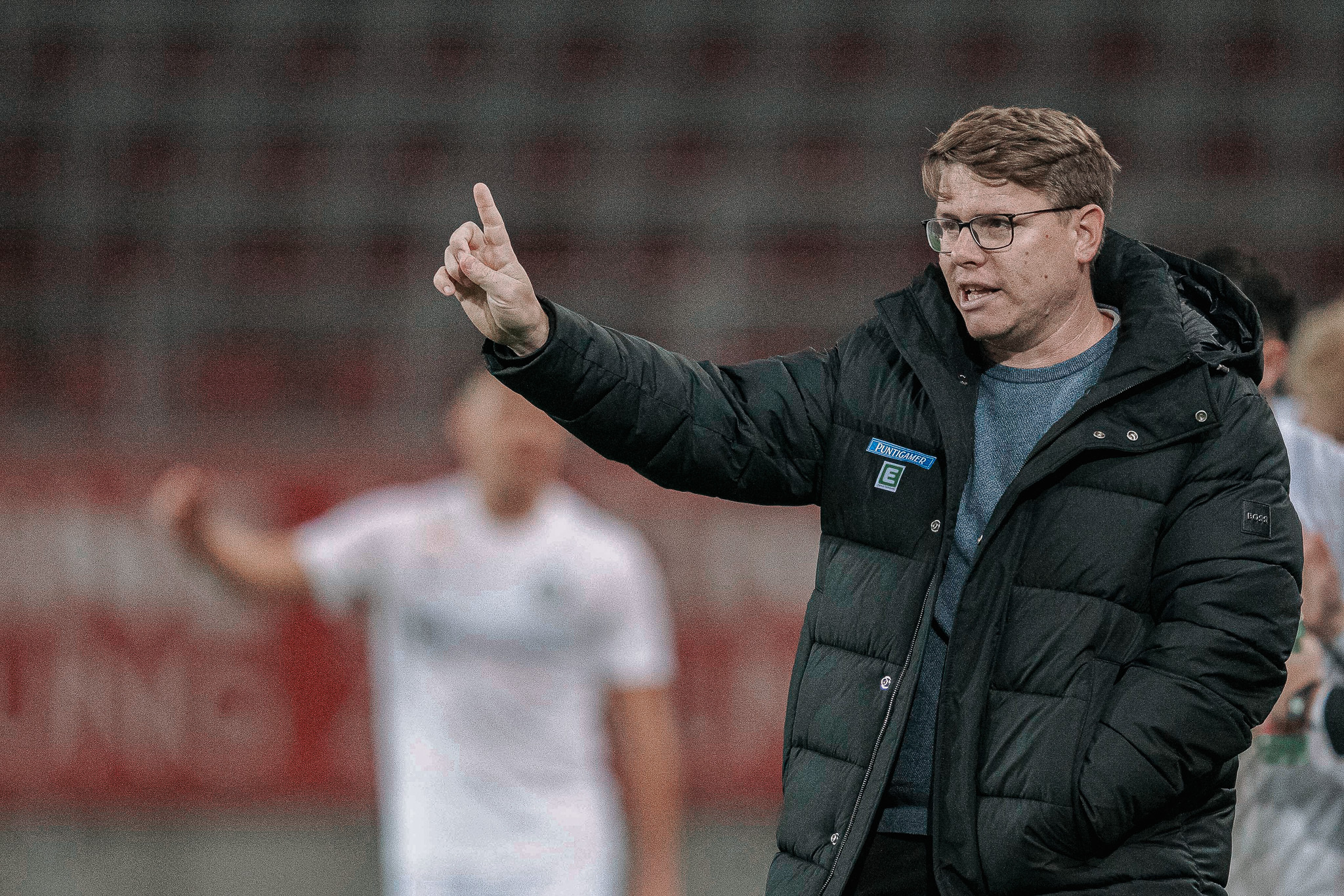 Ein Mann in Jacke zeigt was an.