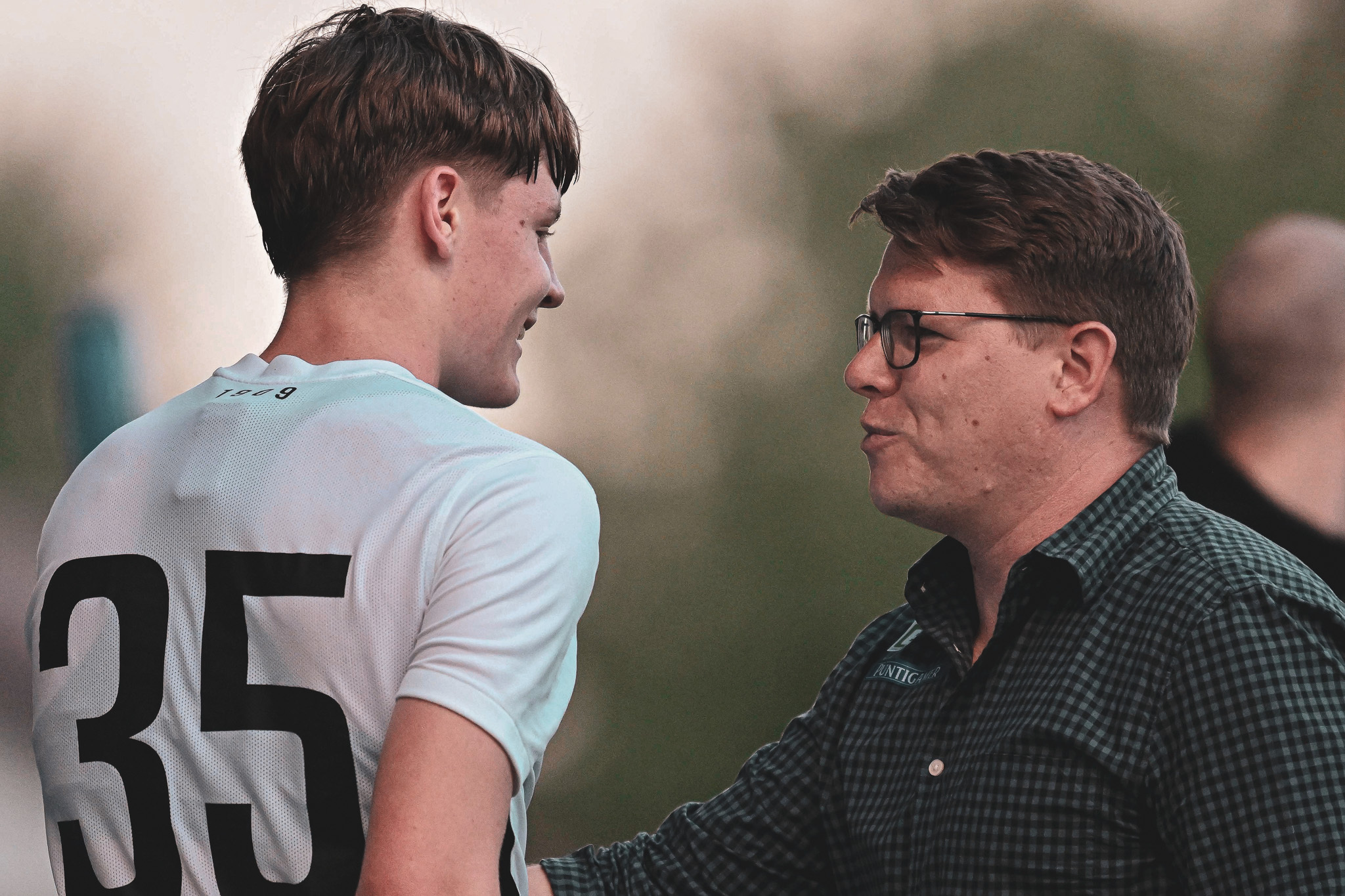 Ein Spieler und ein Trainer unterhalten sich.