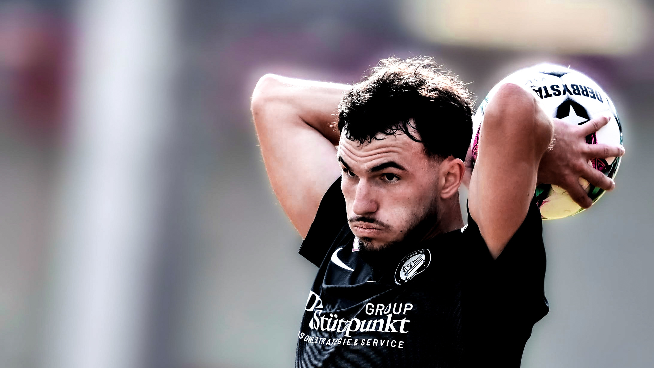 Ein Spieler in schwarzen Trikot wirft einen weißen Ball ein.