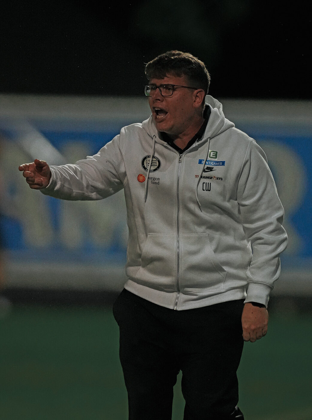 Ein Mann in weißer Jacke ruft.