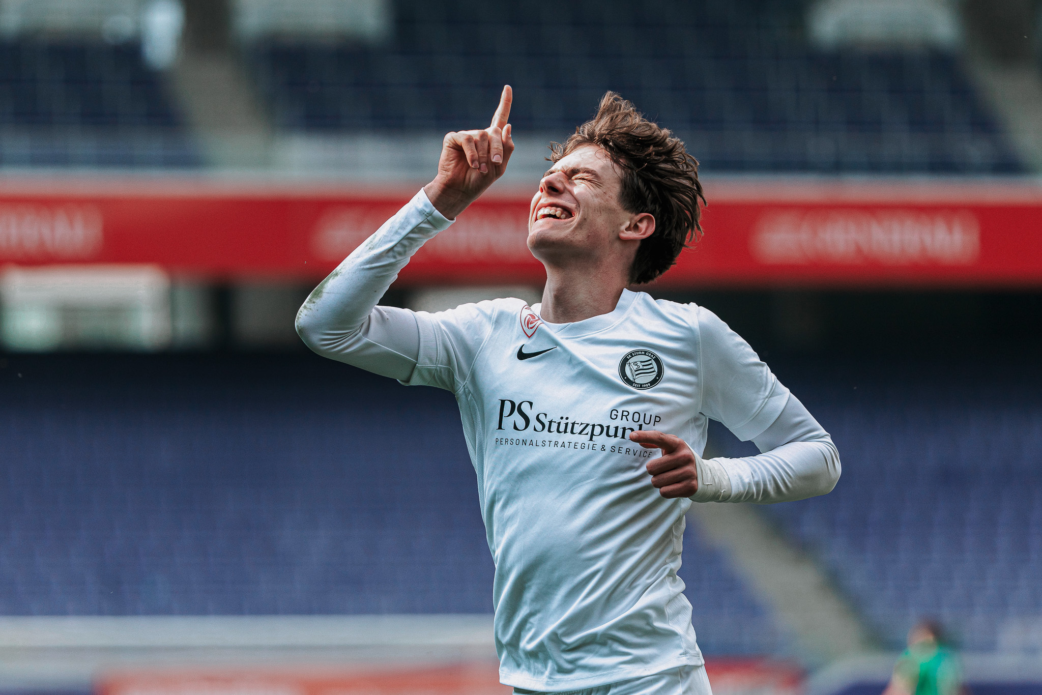 einFußballer jubelt, zeigt zum Himmel.