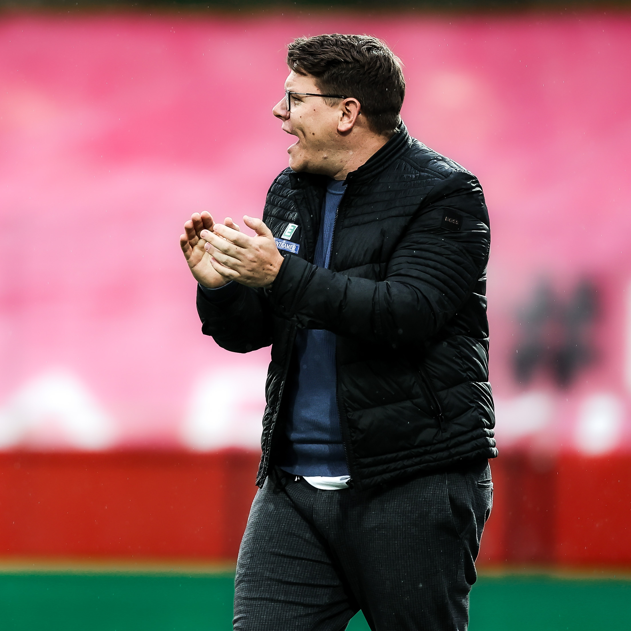 Ein Mann mit Brille und schwarzer Jacke klatscht in die Hände